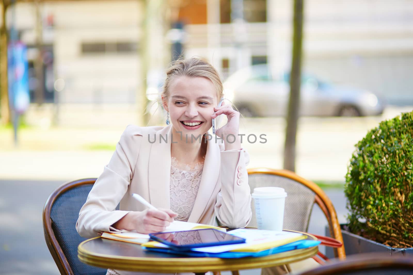 Young businesswoman on a coffee break, working and speaking on the phone