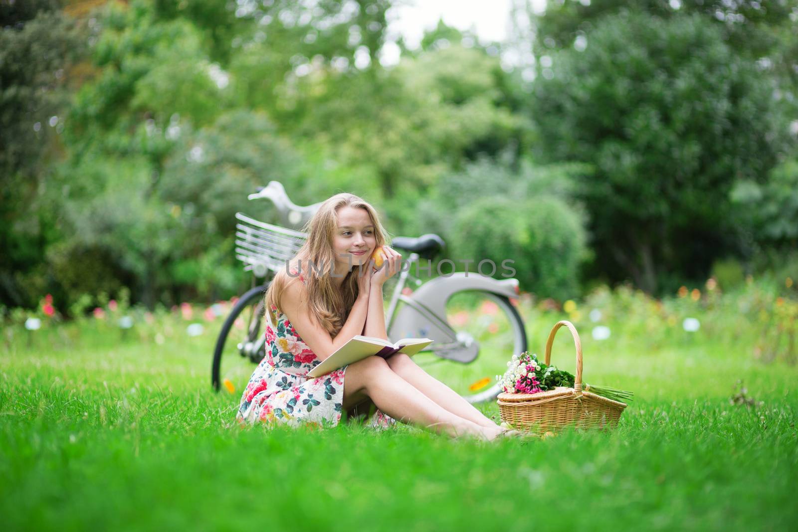 Young girl sitting on the grass and reading a book in the countryside