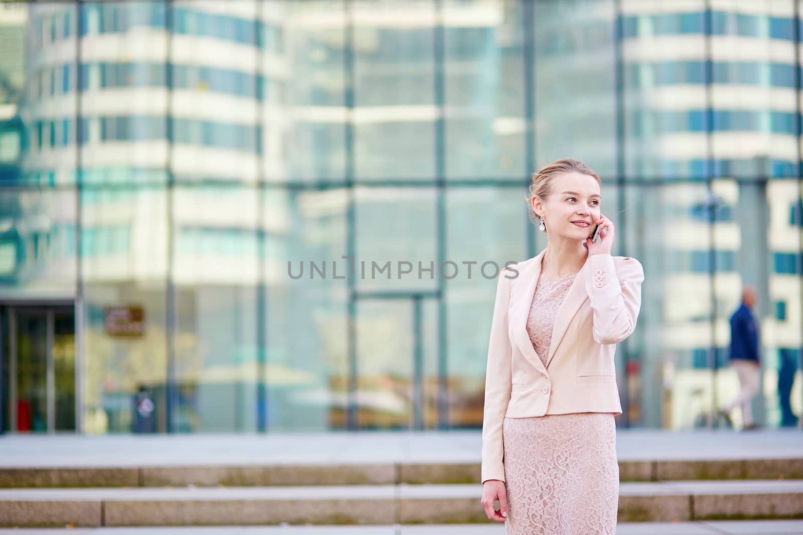 Young confident business woman in modern glass office interior using the mobile phone
