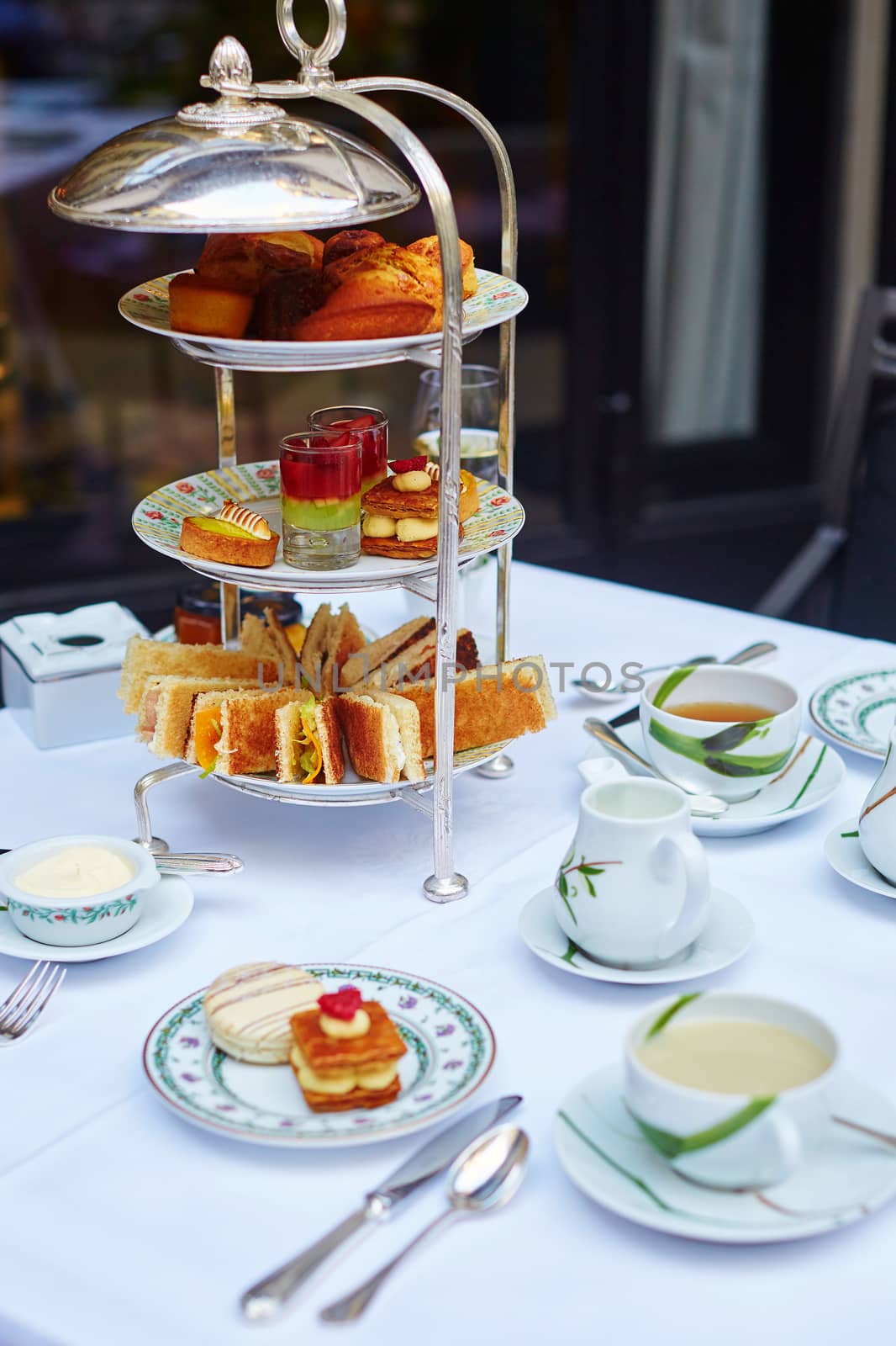 Beautiful table setting with selection of sandwiches, fancy cakes, tea and champagne served for the ceremony of afternoon tea