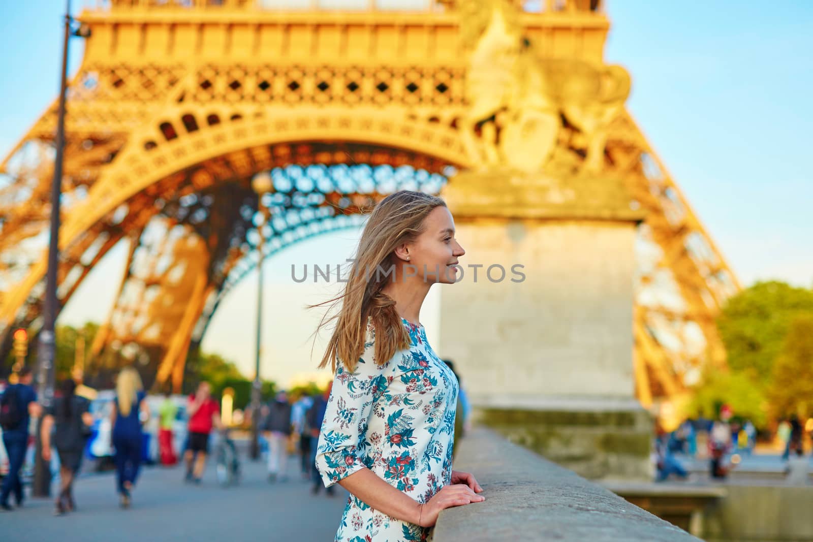 Young beautiful and elegant Parisian woman in blue dress near the Eiffel tower in Paris