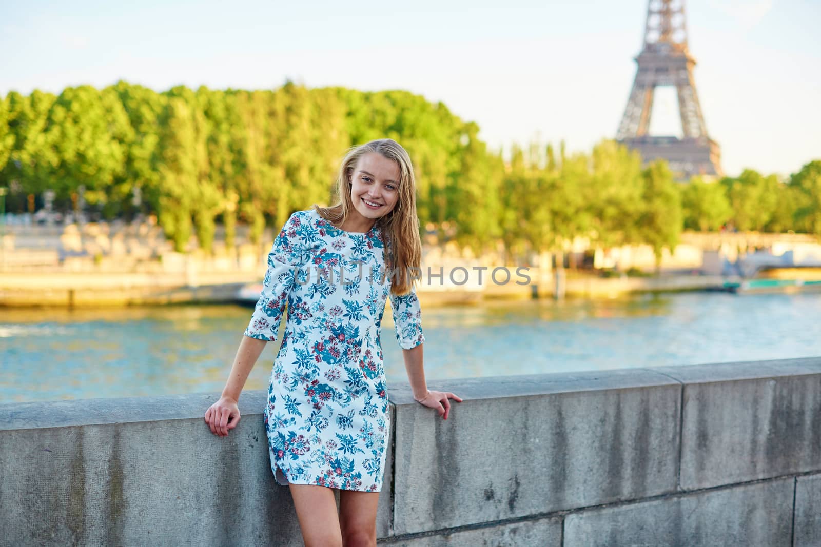 Young beautiful and elegant Parisian woman in blue dress near the Eiffel tower in Paris