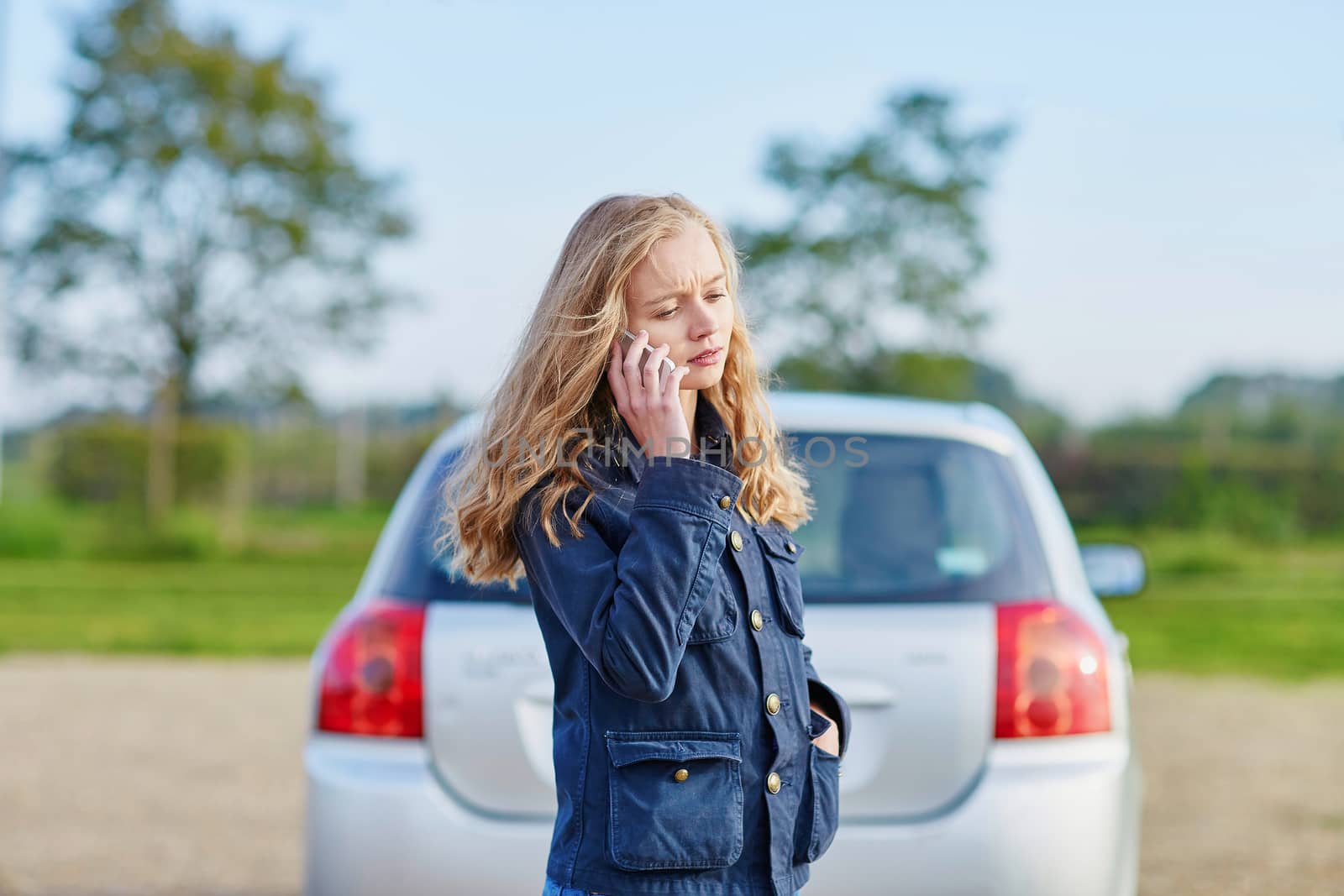 Young woman on the road near a broken car calling for help