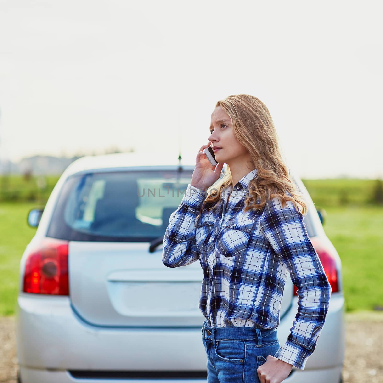 Young woman on the road near a broken car calling for help