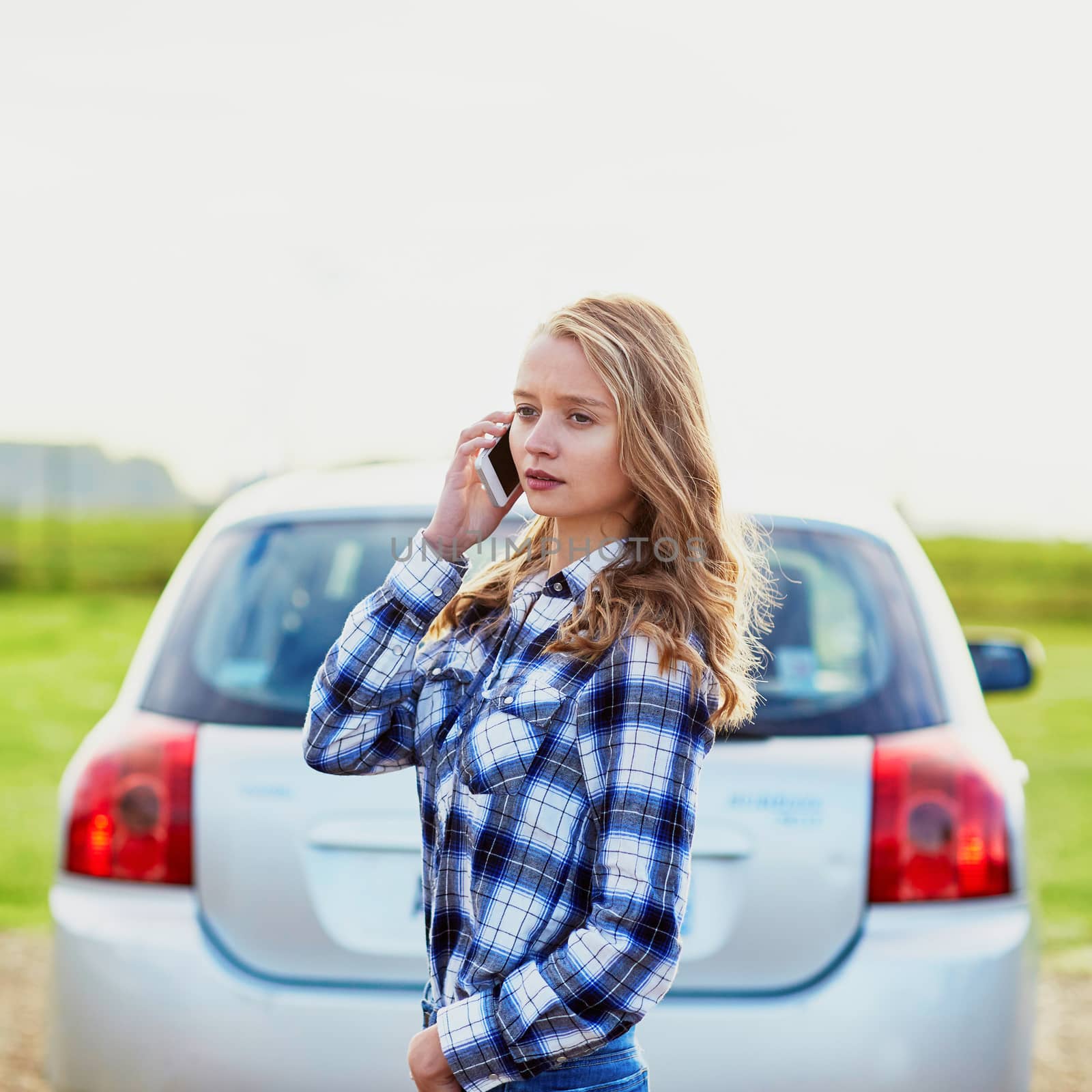 Young woman on the road near a broken car calling for help