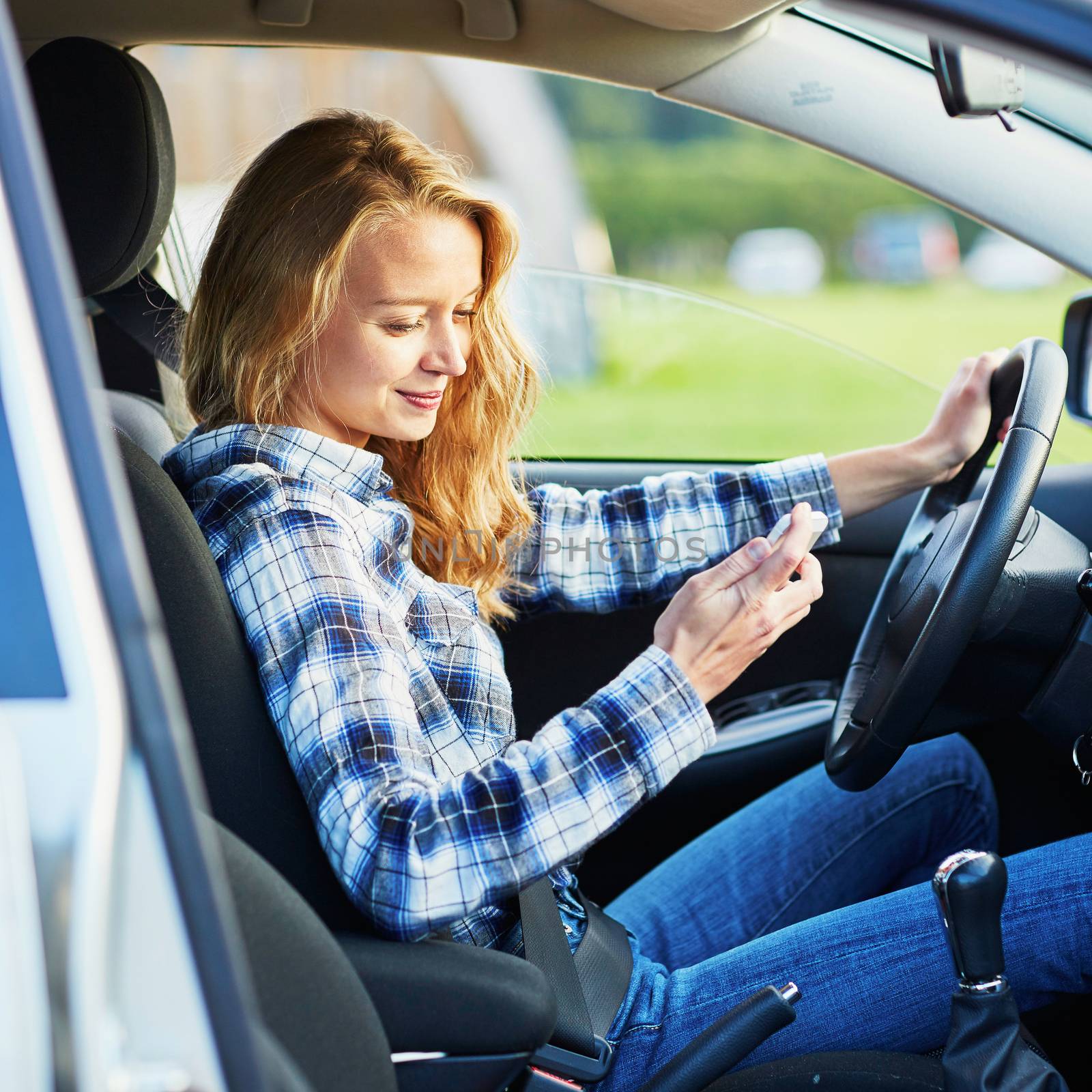 Young woman using her smartphone while driving a car