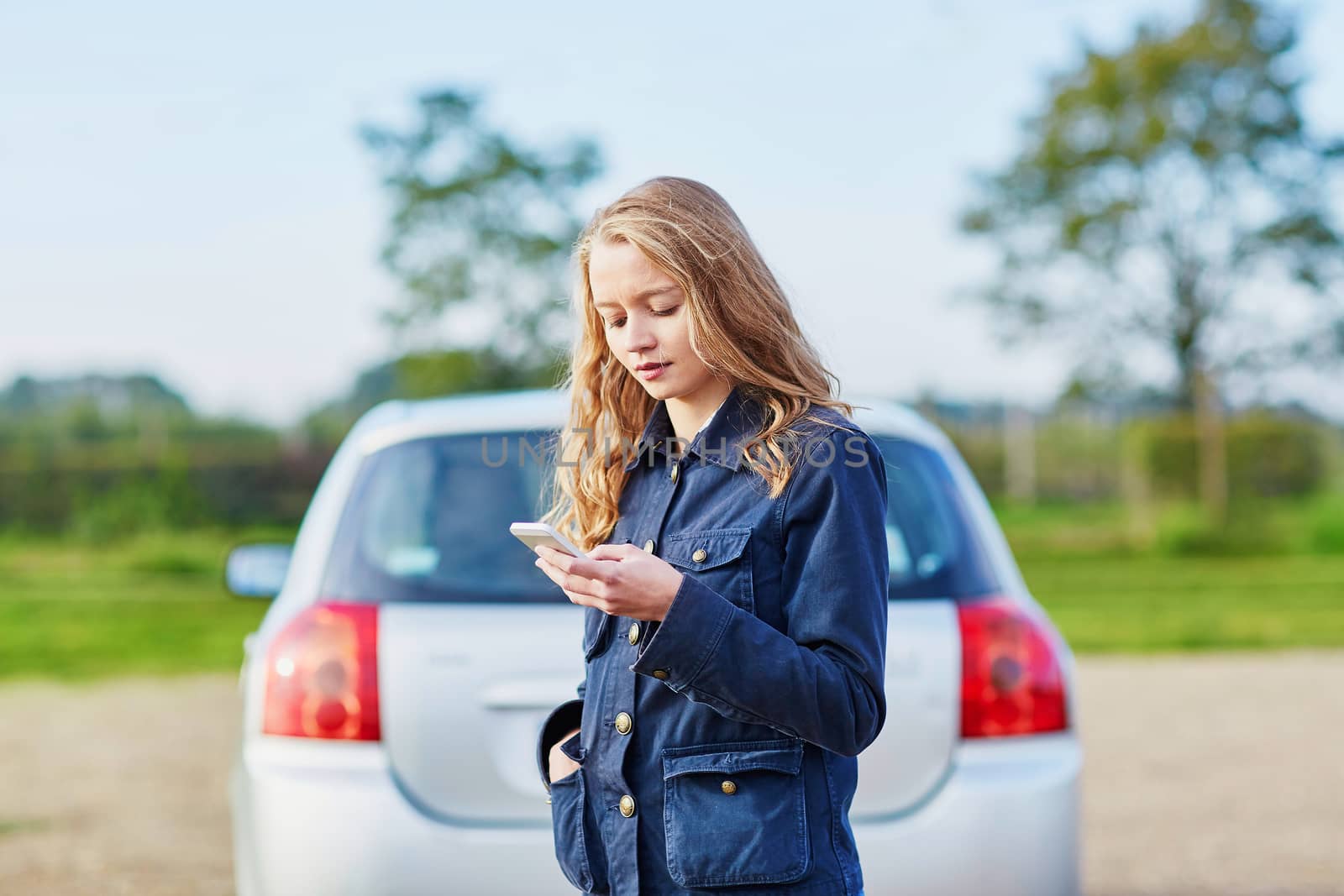 Young woman on the road near a broken car calling for help