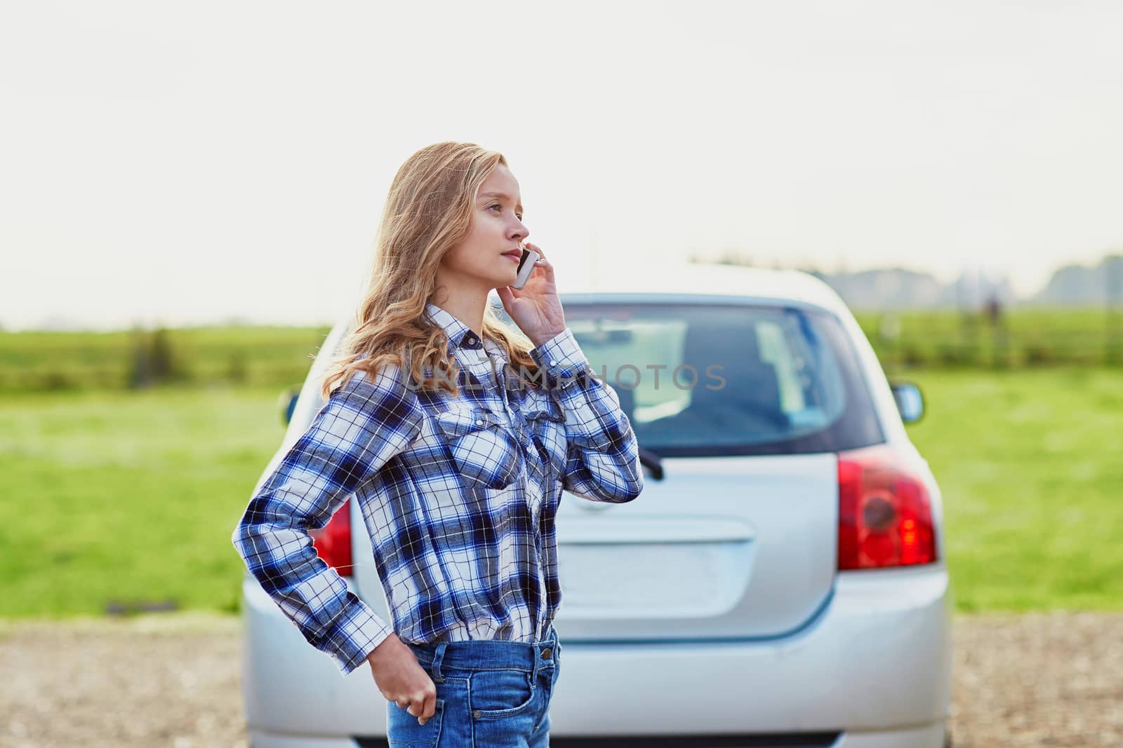 Young woman on the road near a broken car calling for help