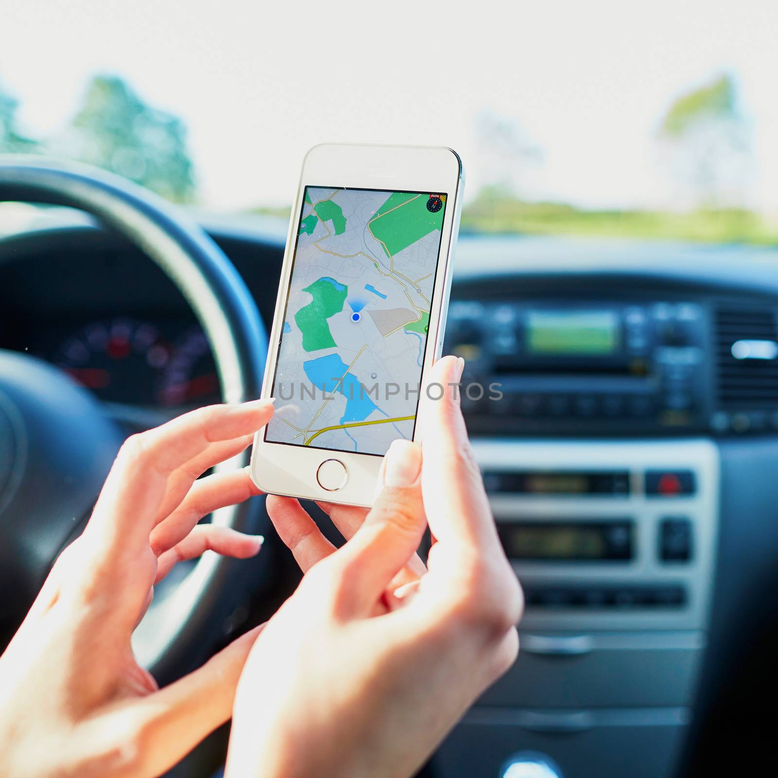 Female driver hands holding a phone with interface navigator on a screen