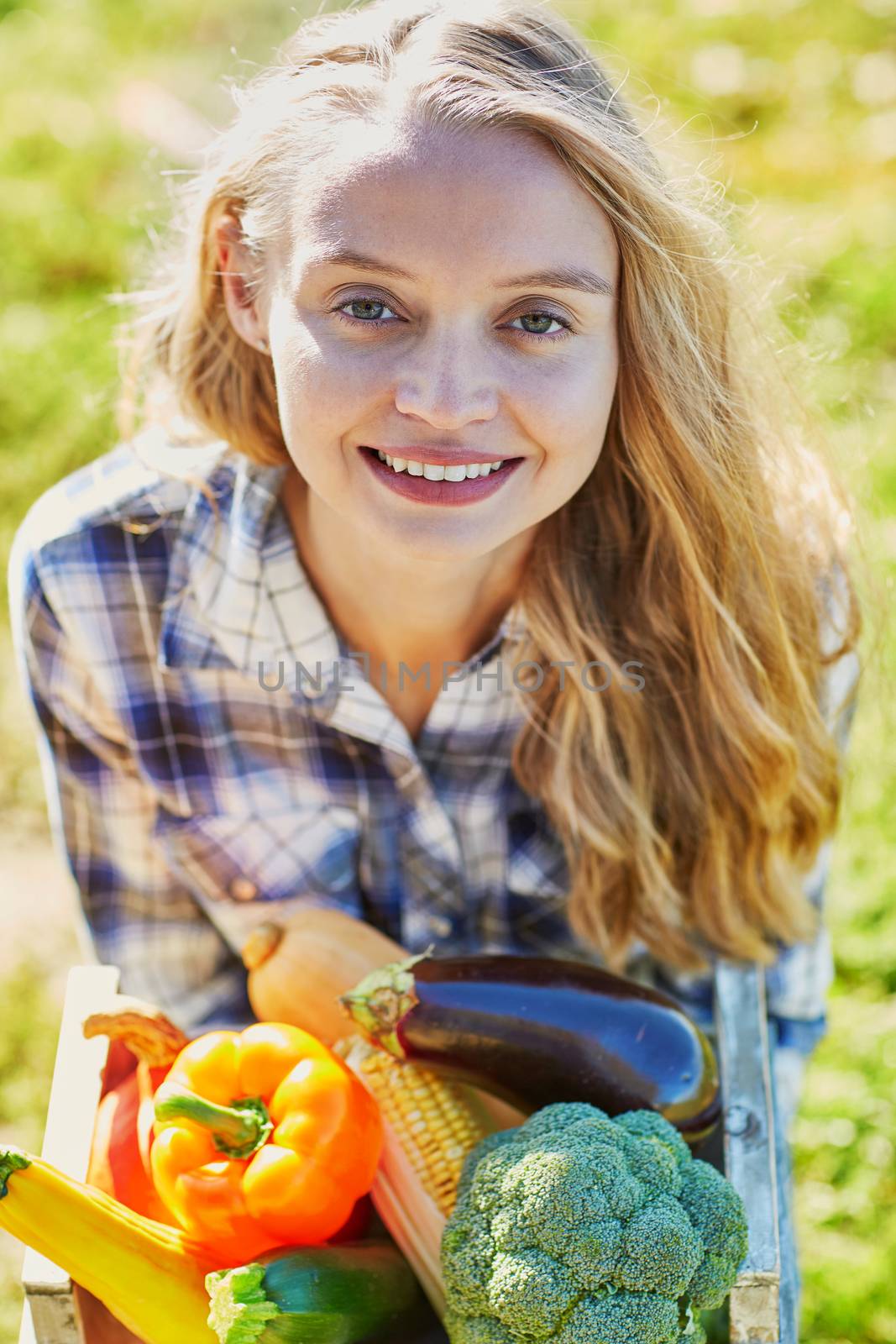 Woman holding wooden crate with fresh organic vegetables from farm