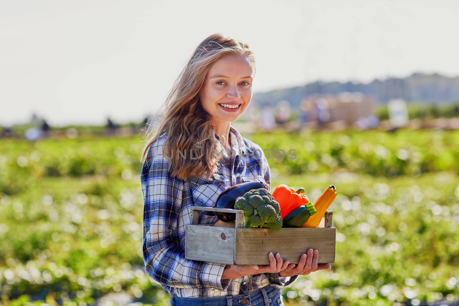 Woman holding wooden crate with fresh organic vegetables from farm