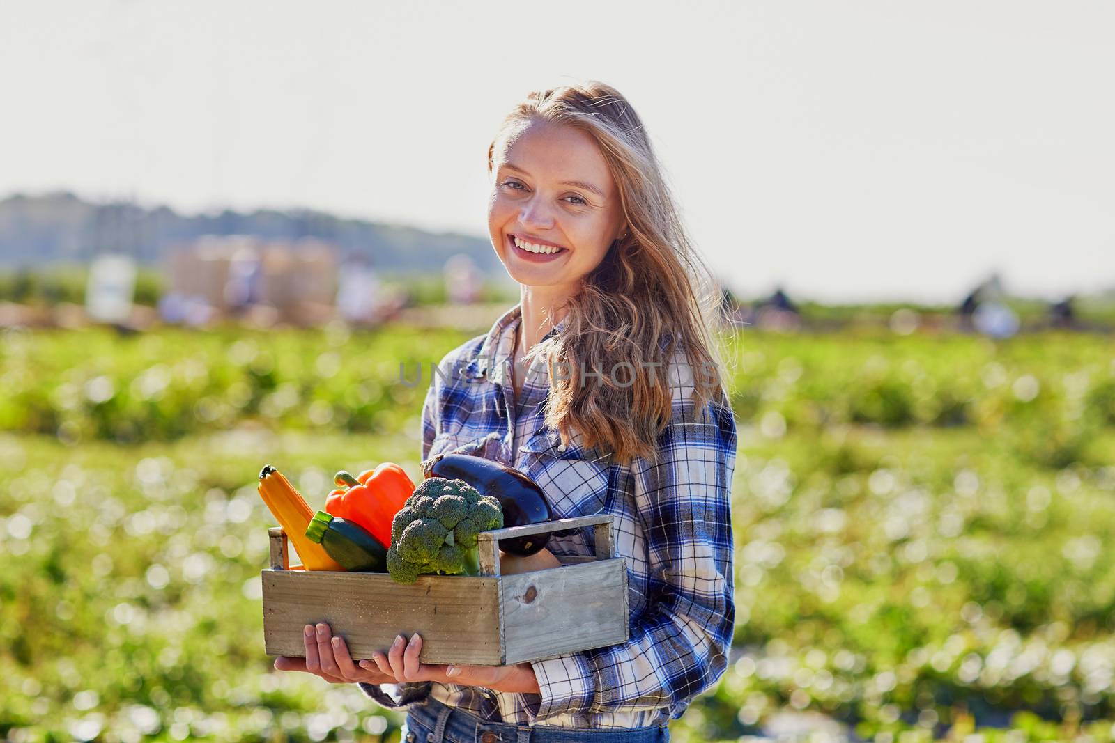Woman holding wooden crate with fresh organic vegetables from farm