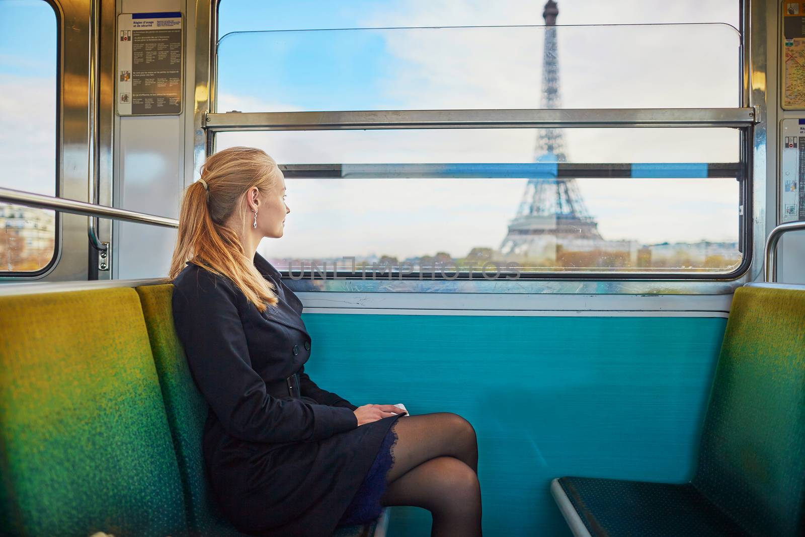Beautiful young woman travelling in a train of Parisian underground and looking through the window at the Eiffel tower