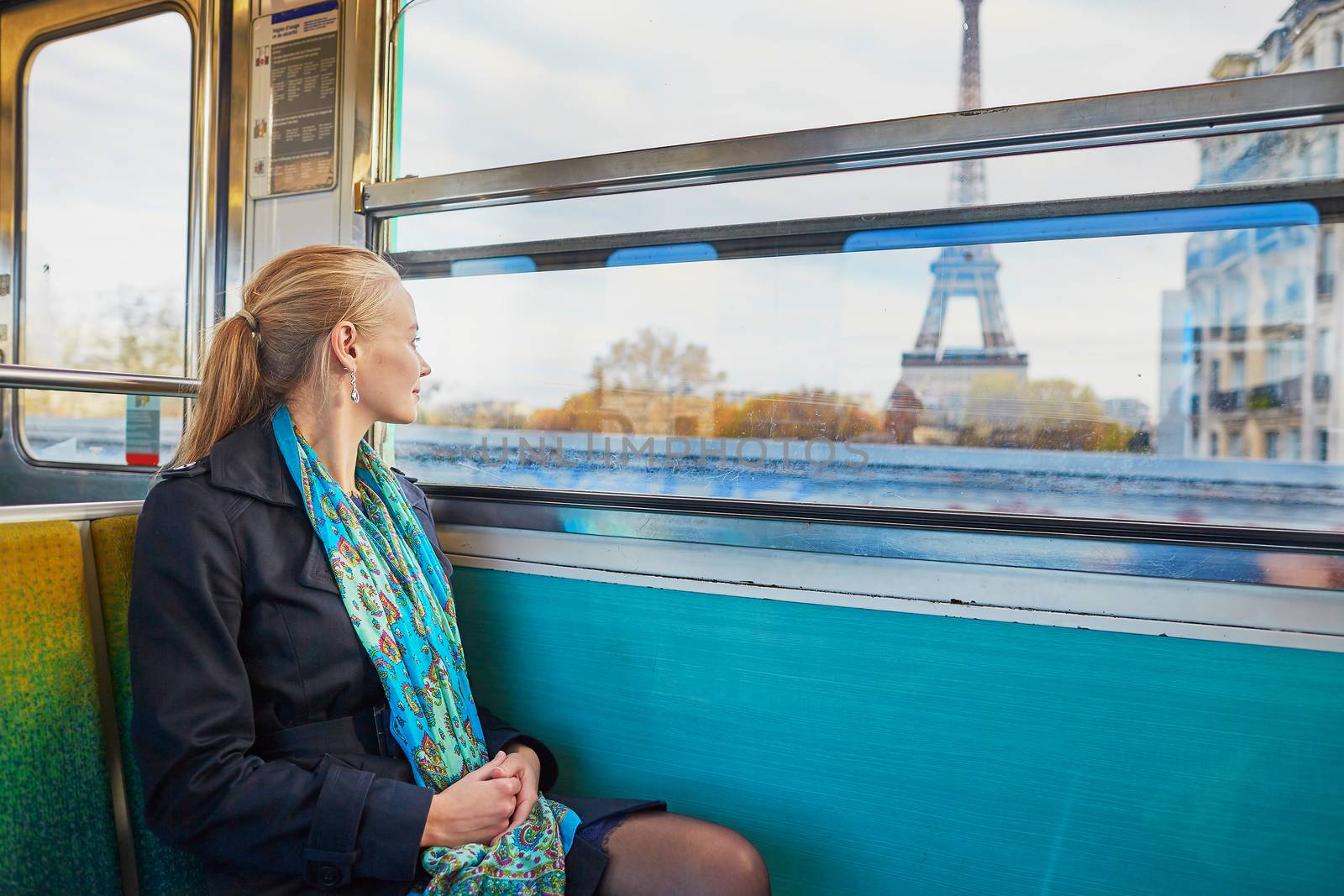 Beautiful young woman travelling in a train of Parisian underground and looking through the window at the Eiffel tower