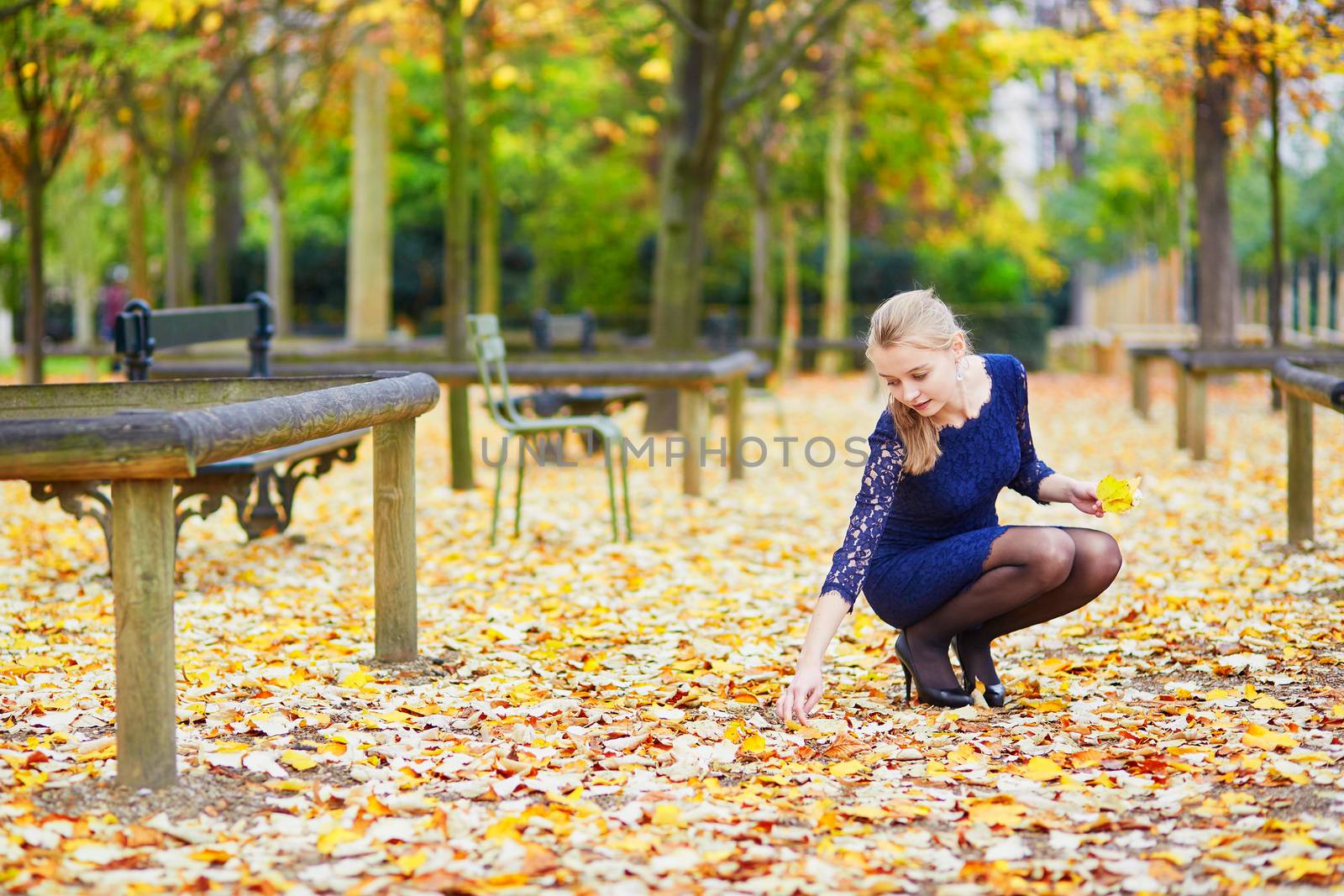 Beautiful young woman in blue dress in the Luxembourg garden of Paris on a fall day