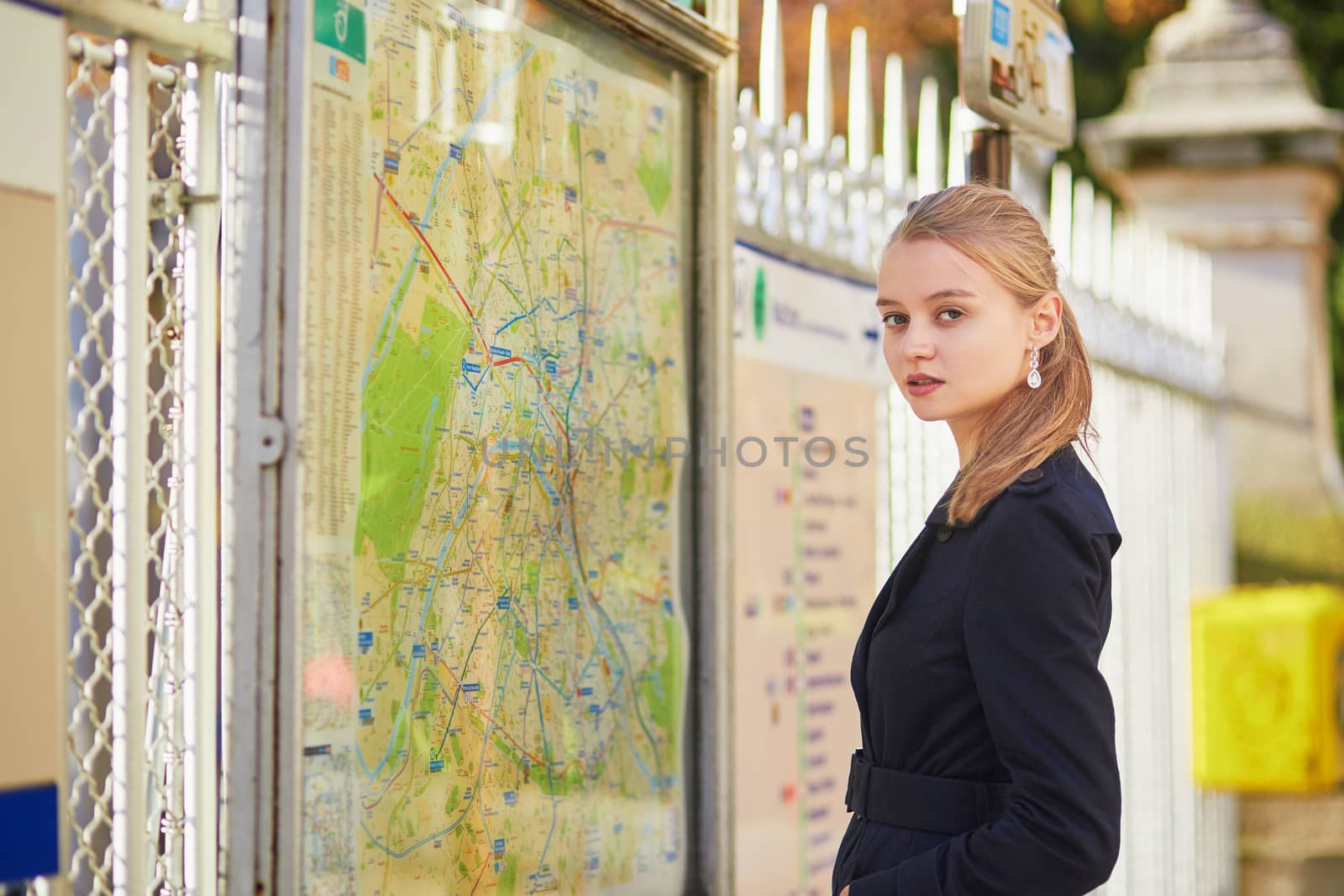 Young beautiful Parisian woman near the subway plan, looking for the direction
