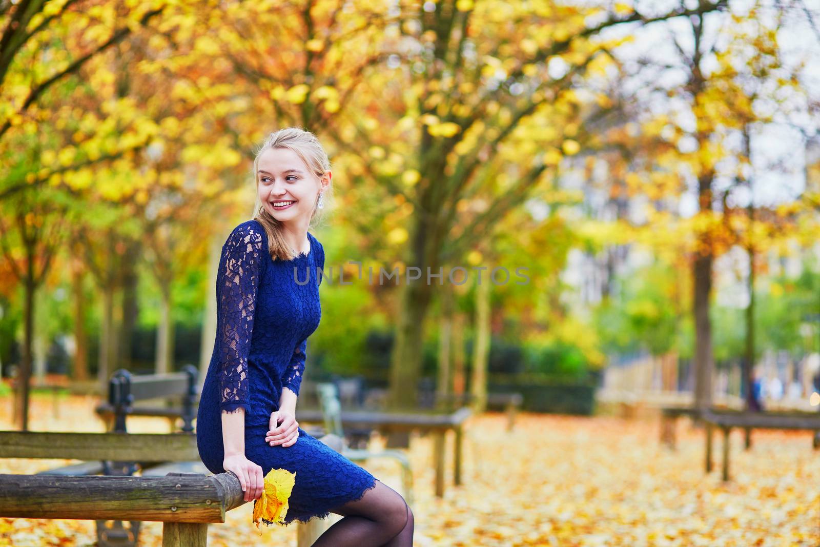 Beautiful young woman in blue dress in the Luxembourg garden of Paris on a fall day