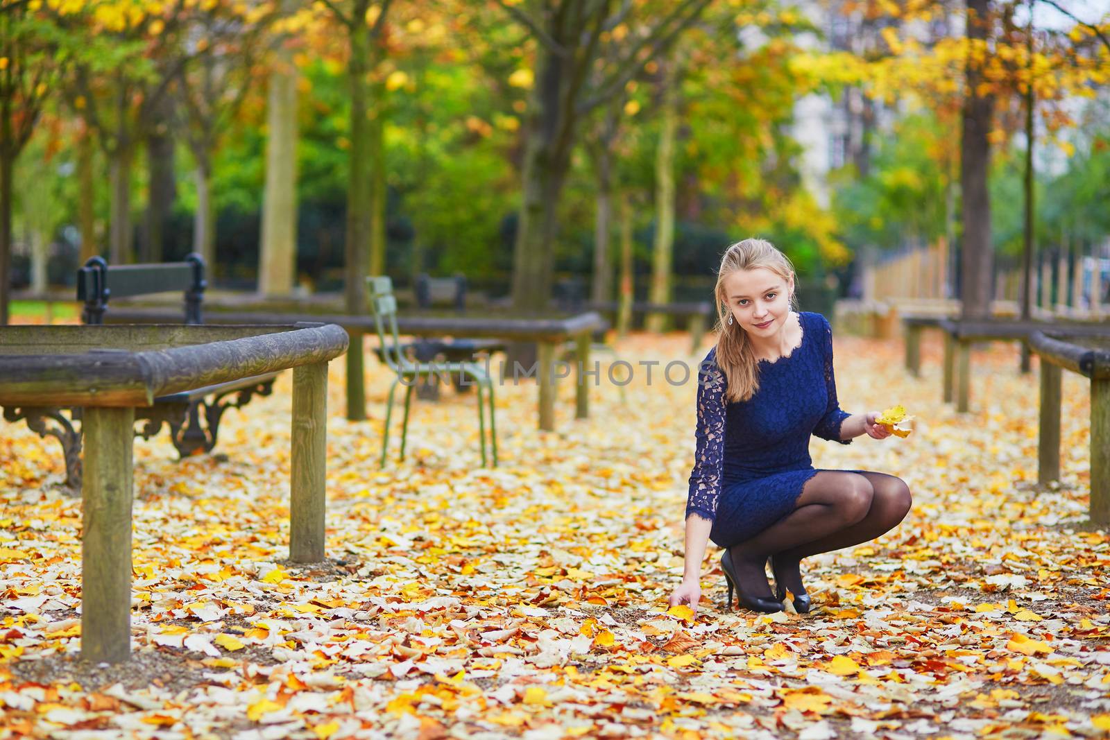 Beautiful young woman in blue dress in the Luxembourg garden of Paris on a fall day