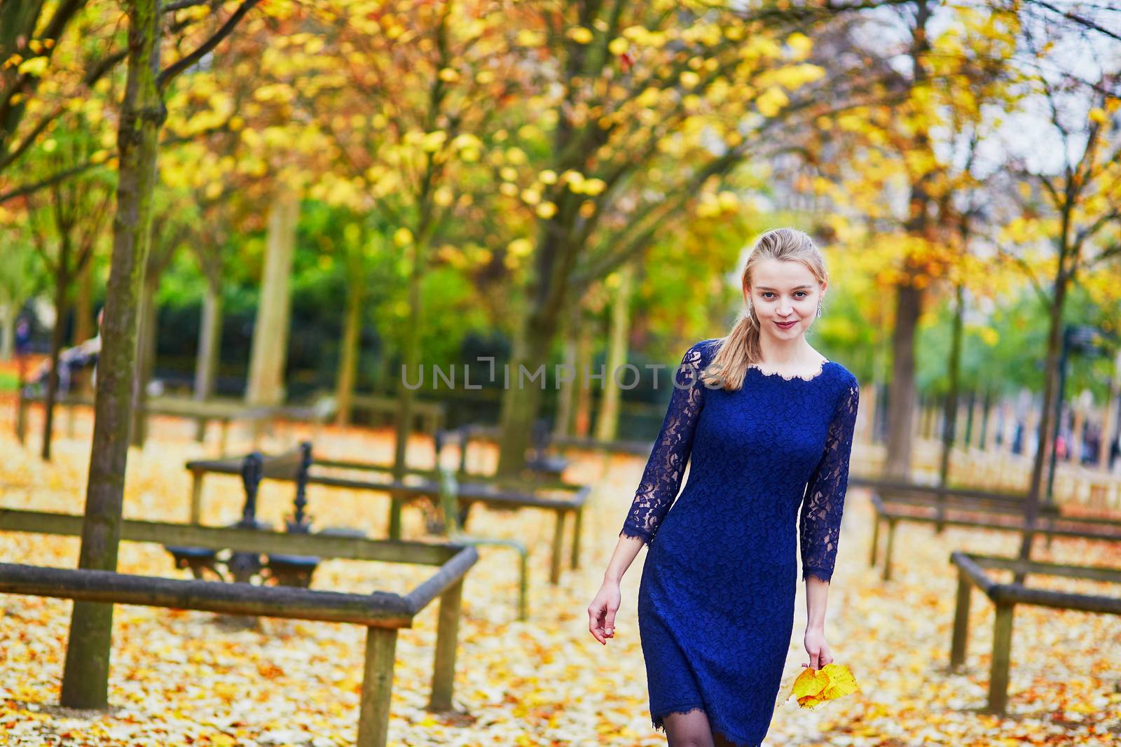 Beautiful young woman in blue dress in the Luxembourg garden of Paris on a fall day