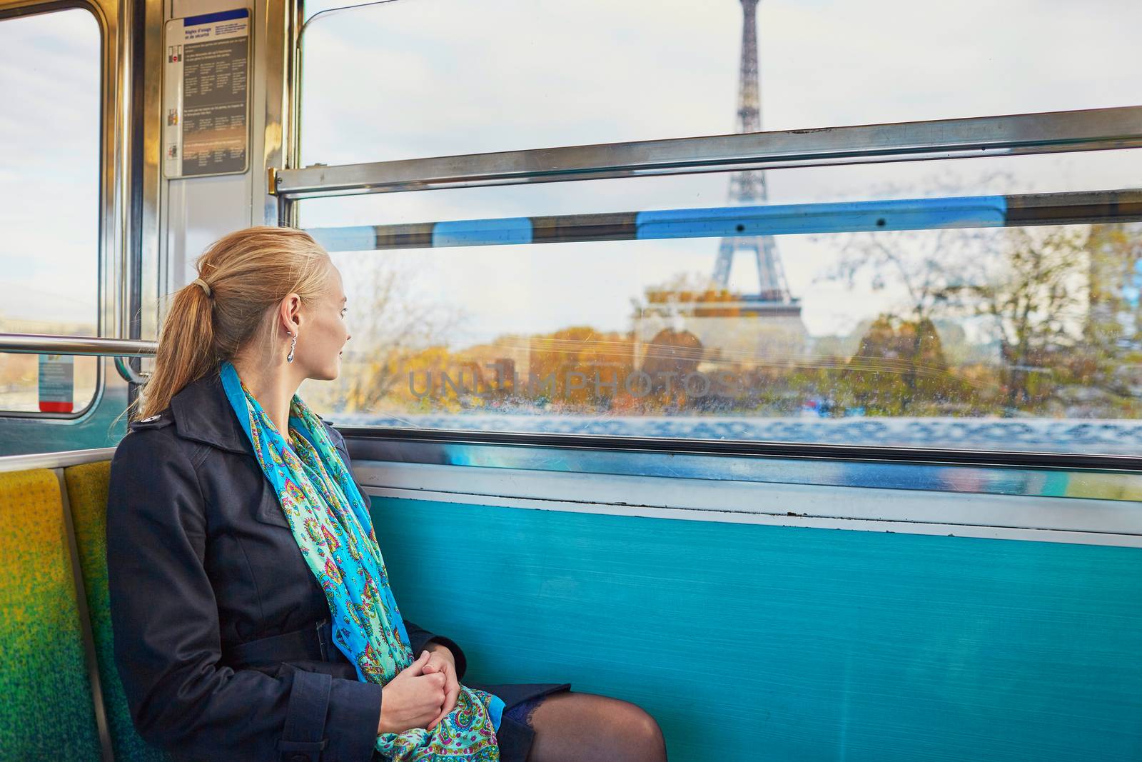 Beautiful young woman travelling in a train of Parisian underground and looking through the window at the Eiffel tower