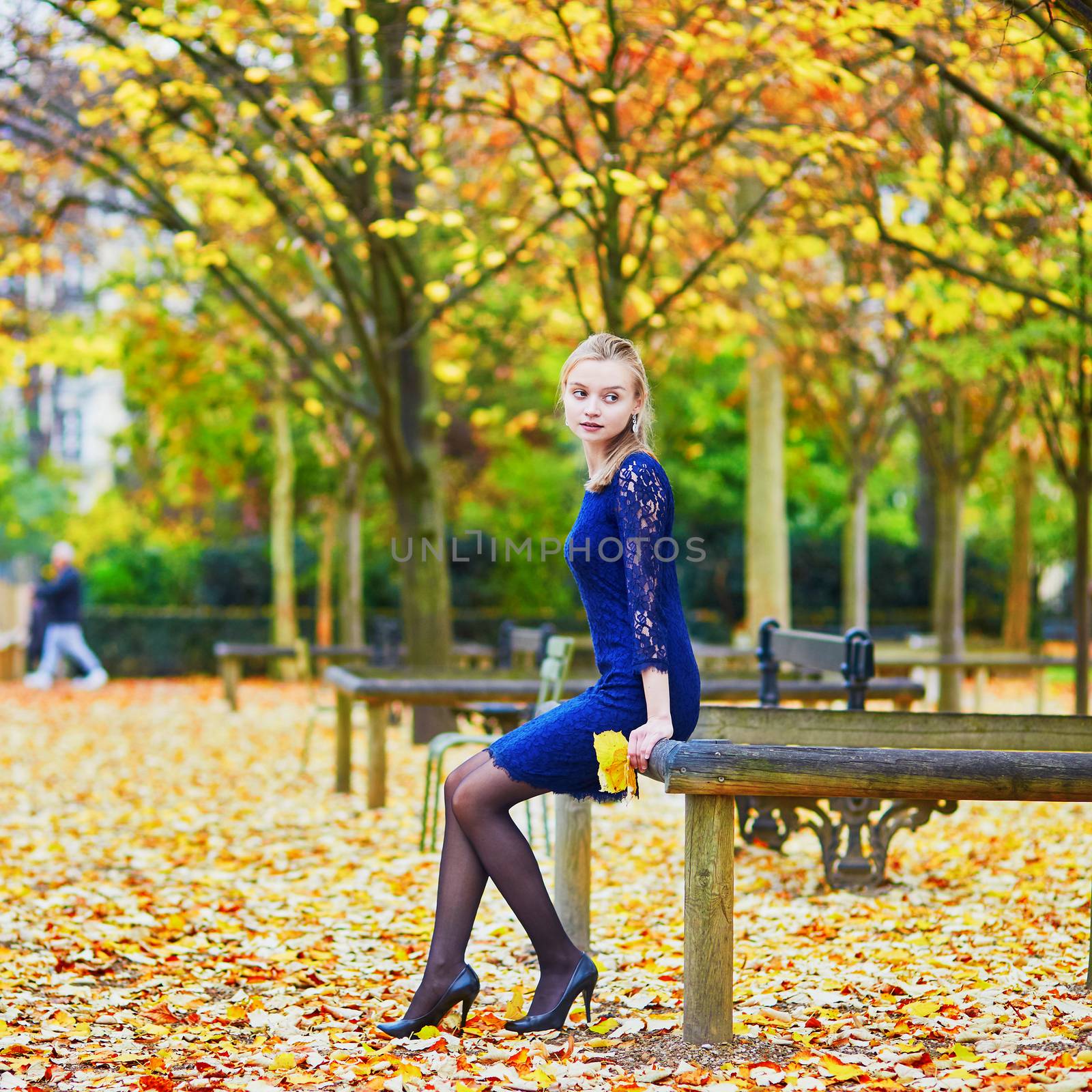 Beautiful young woman in blue dress in the Luxembourg garden of Paris on a fall day