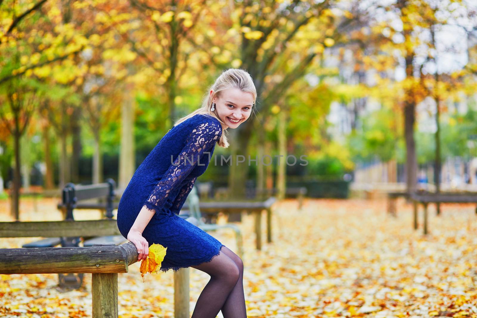 Beautiful young woman in blue dress in the Luxembourg garden of Paris on a fall day