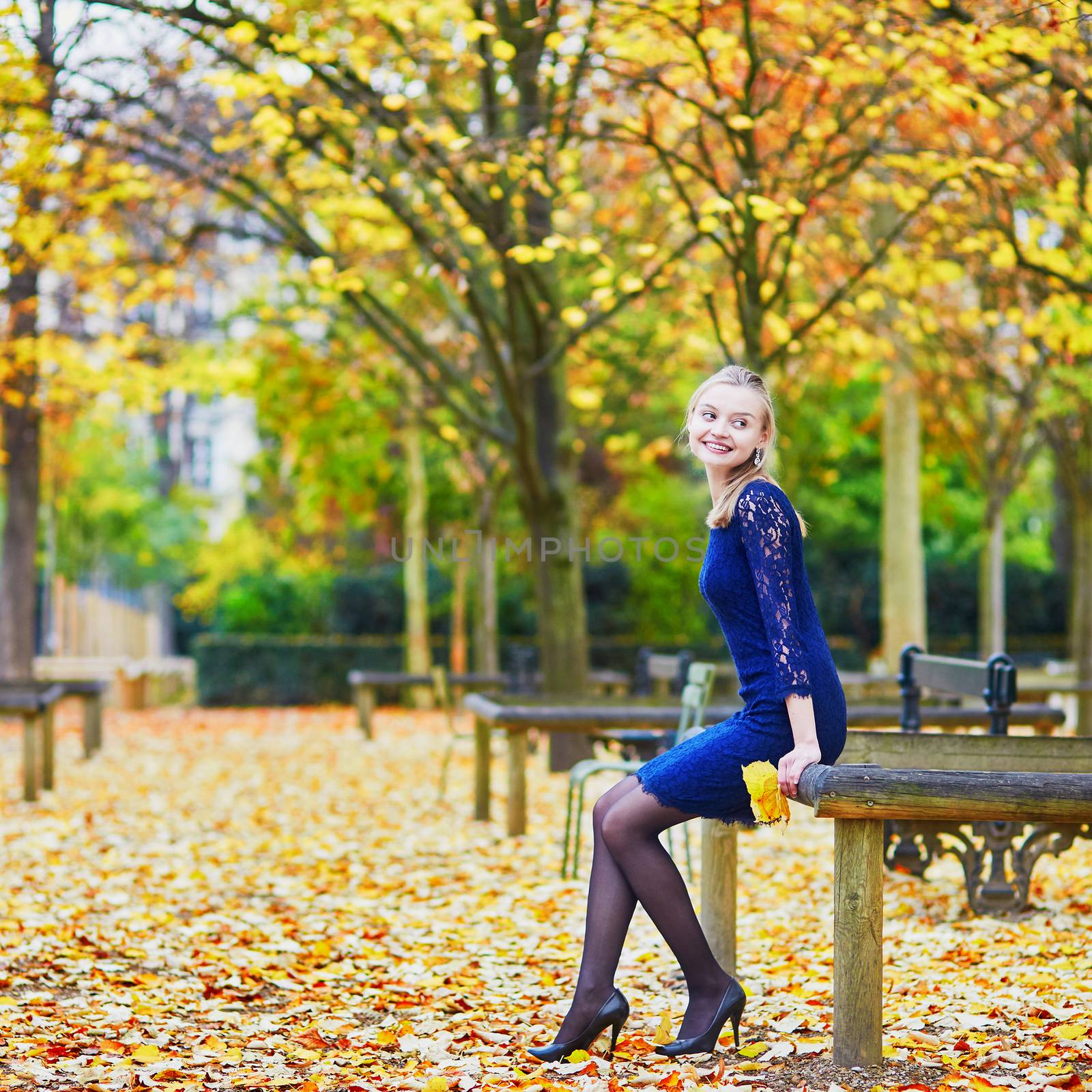 Beautiful young woman in blue dress in the Luxembourg garden of Paris on a fall day