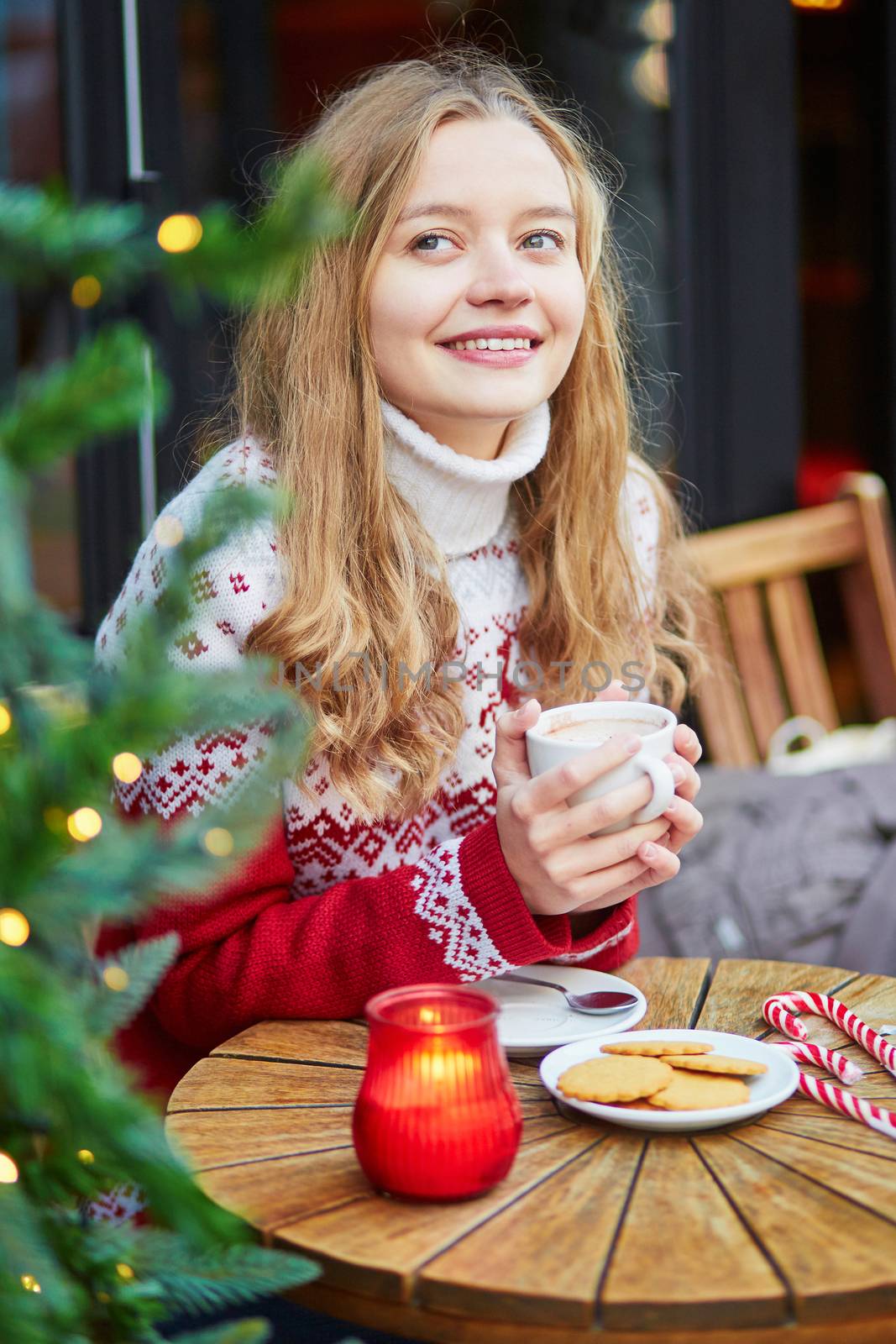 Beautiful young girl in an outdoor Parisian cafe on a winter day, drinking hot chocolate