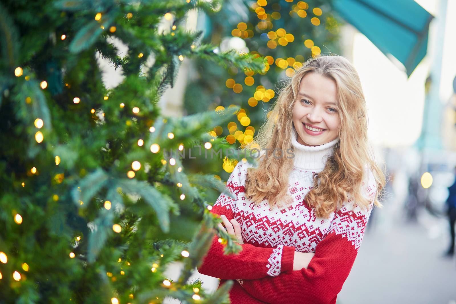 Cheerful young woman on a street of Paris decorated for Christmas