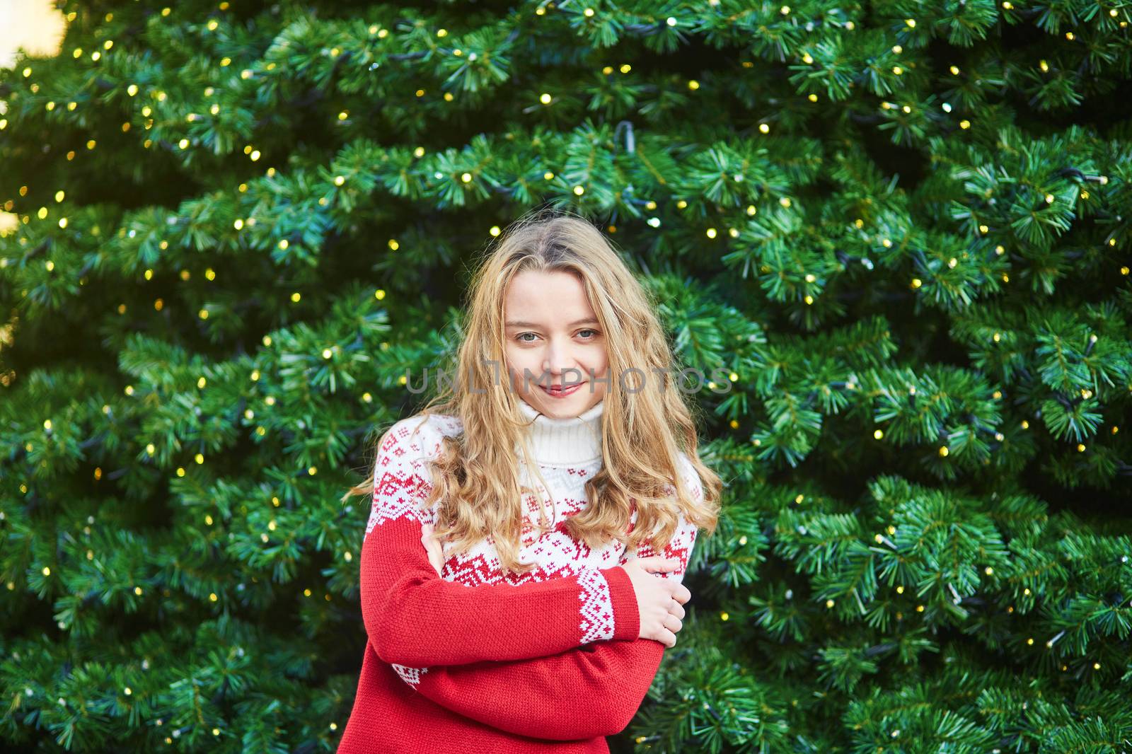Cheerful young woman on a street of Paris decorated for Christmas