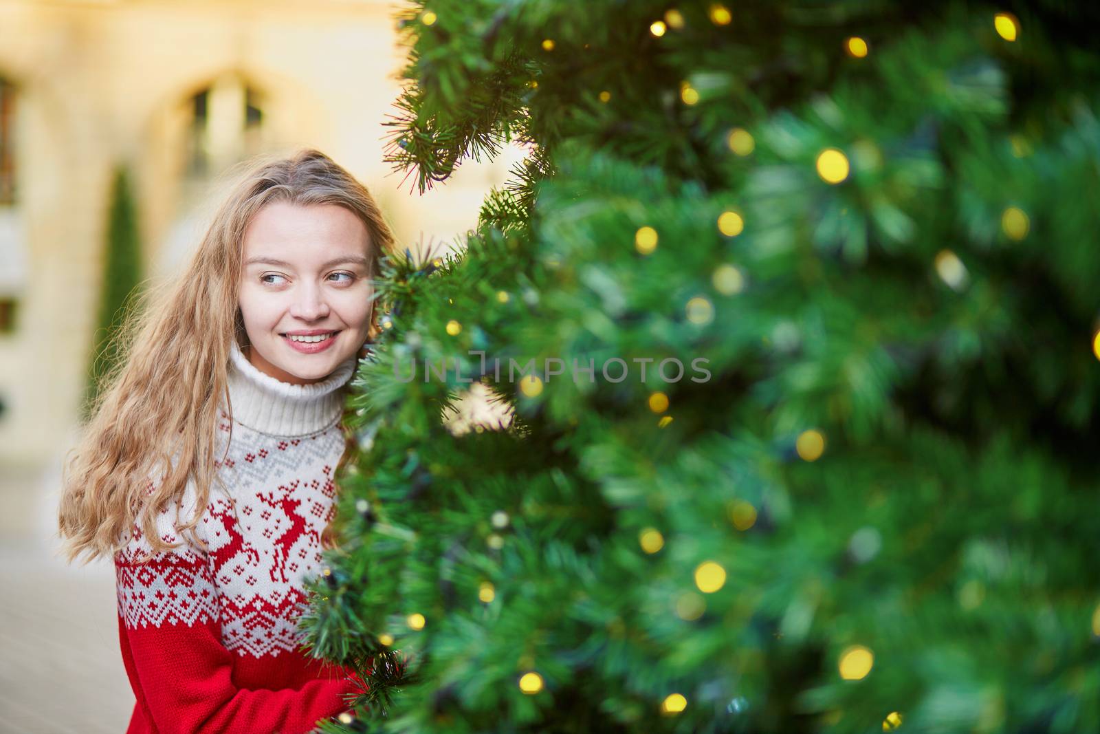 Cheerful young woman on a street of Paris decorated for Christmas