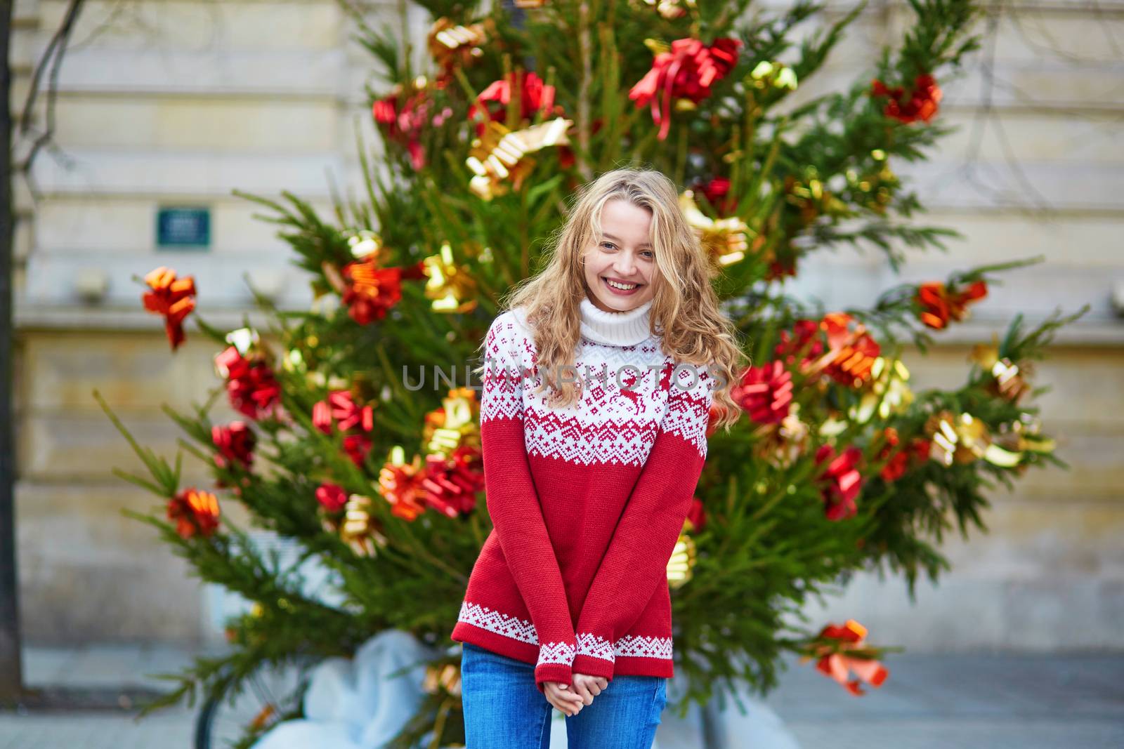 Girl with a brightly decorated Christmas tree in Paris