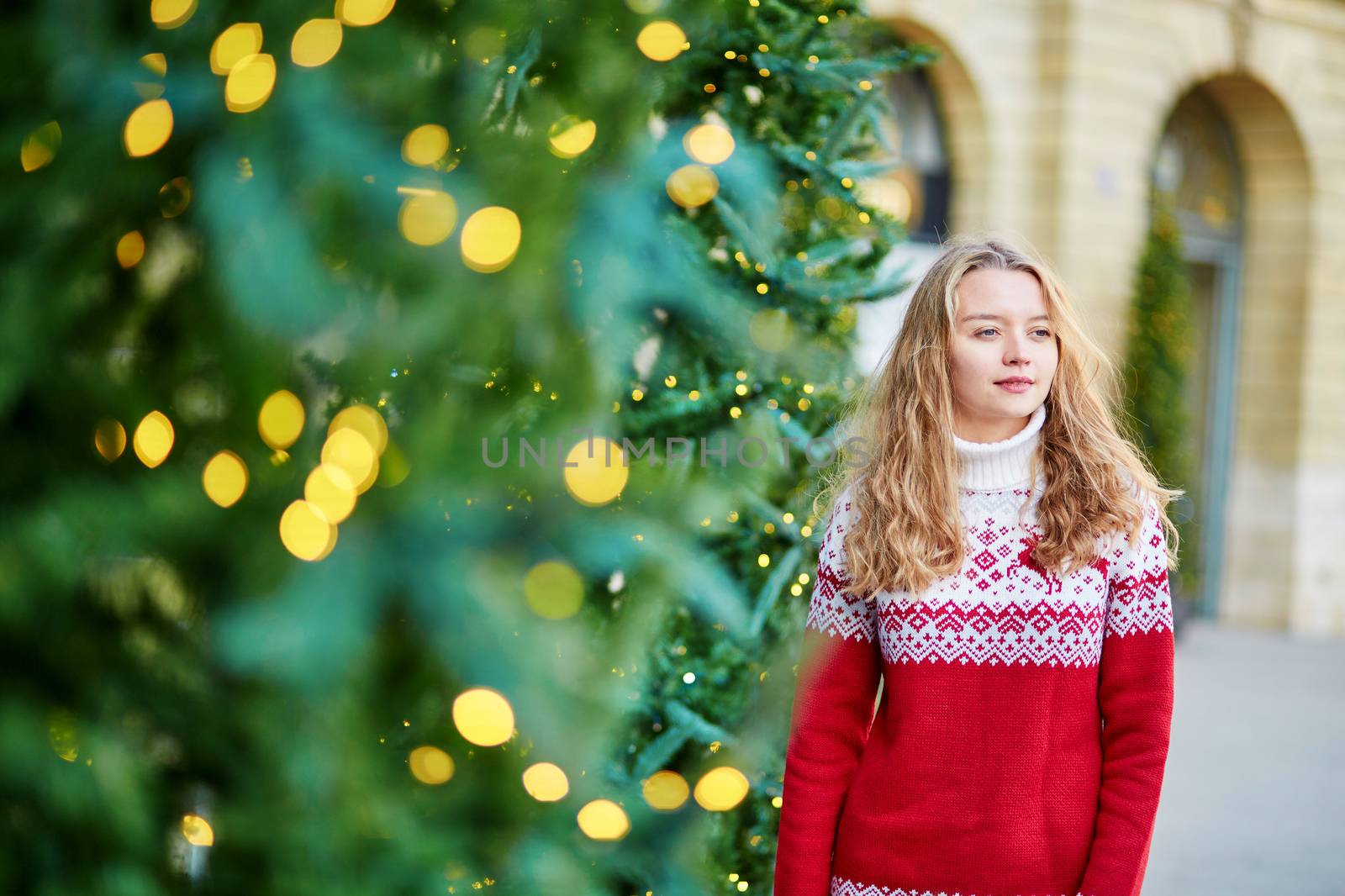 Cheerful young woman on a street of Paris decorated for Christmas