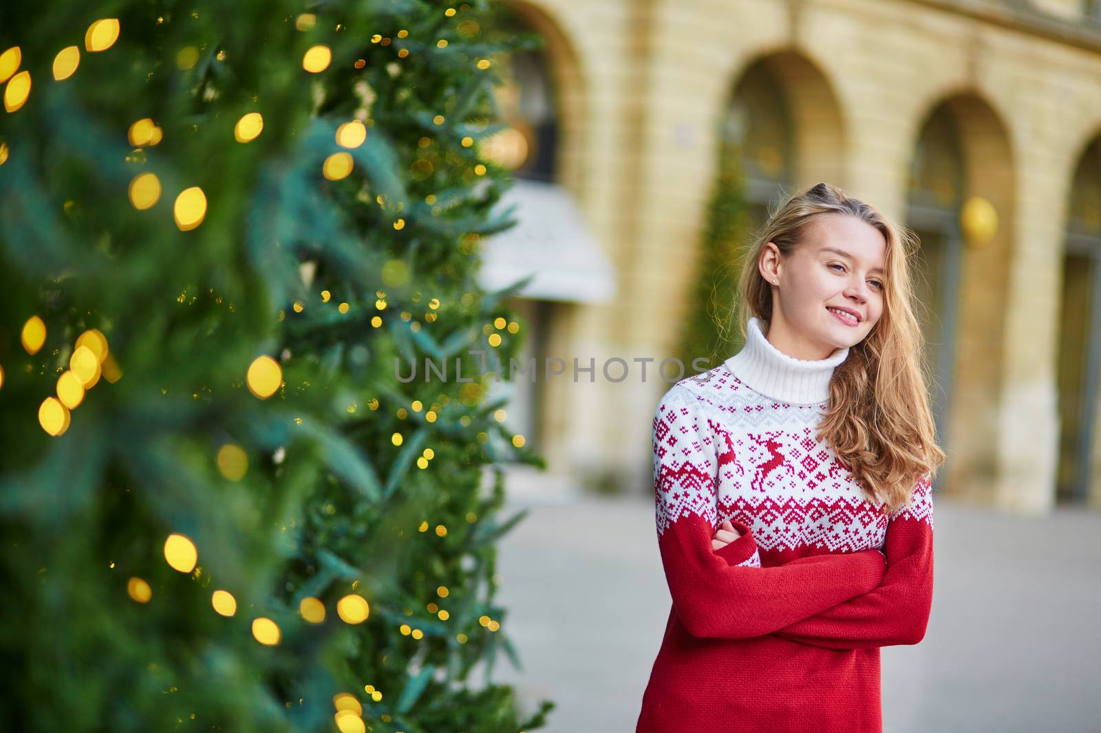 Cheerful young woman on a street of Paris decorated for Christmas