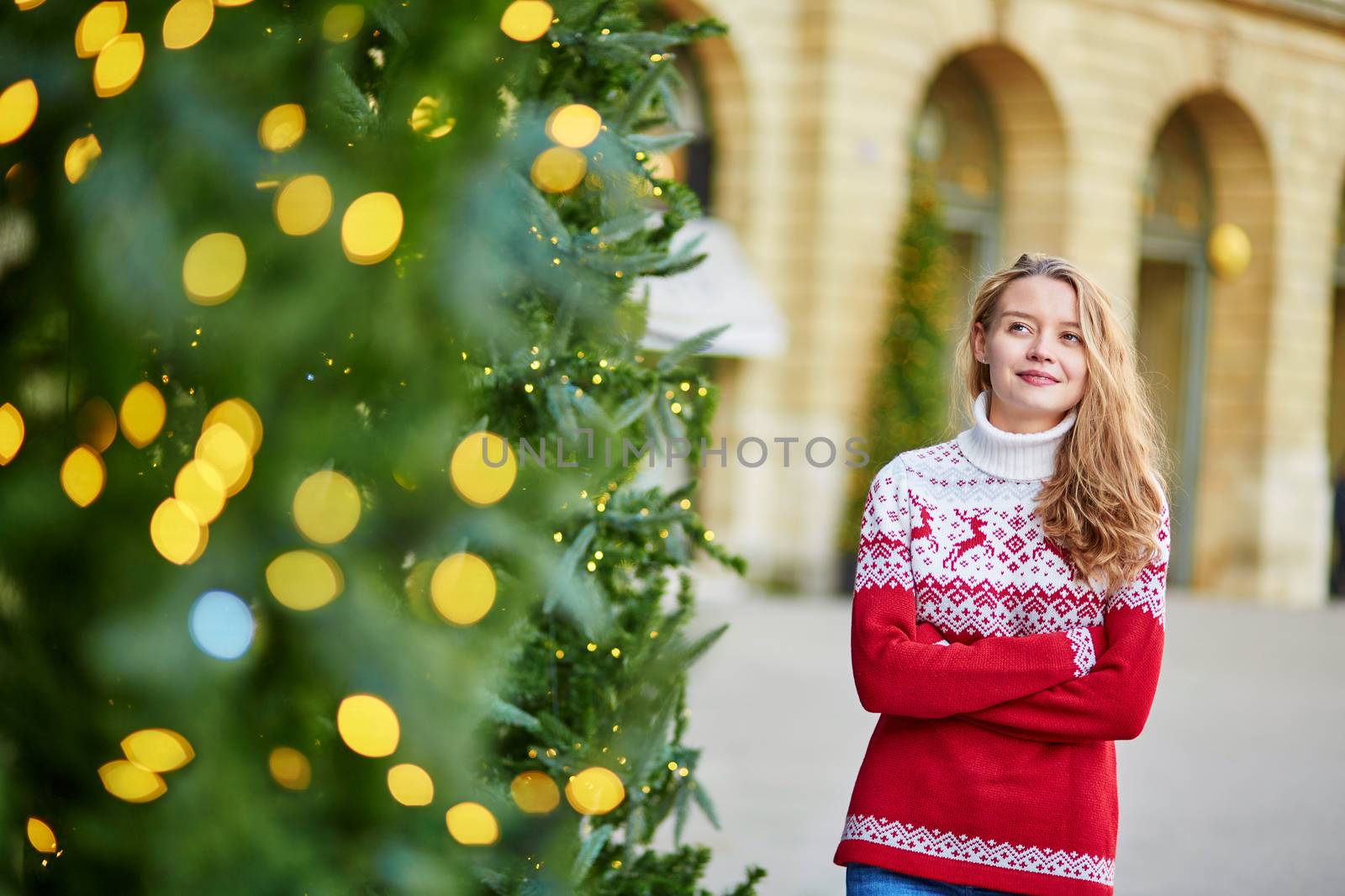 Girl with a brightly decorated Christmas tree in Paris