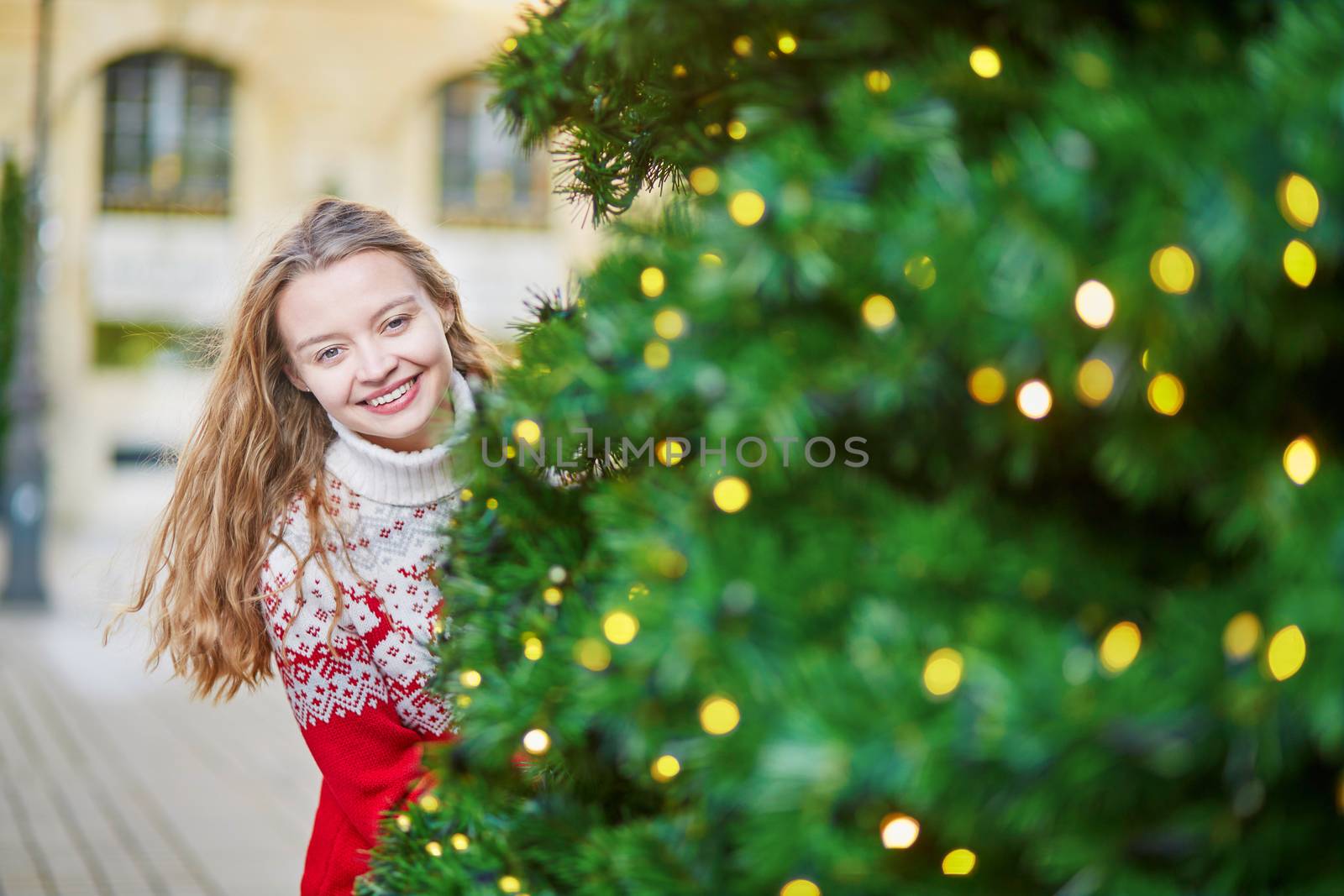 Cheerful young woman on a street of Paris decorated for Christmas