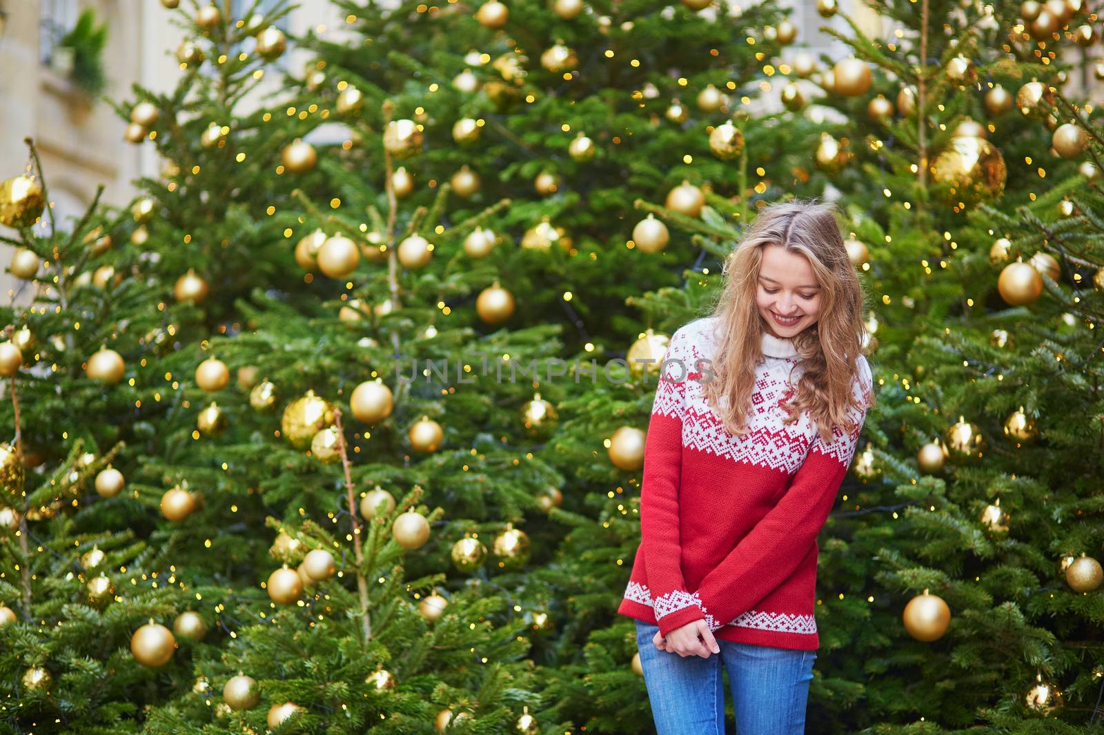 Cheerful young woman on a street of Paris decorated for Christmas