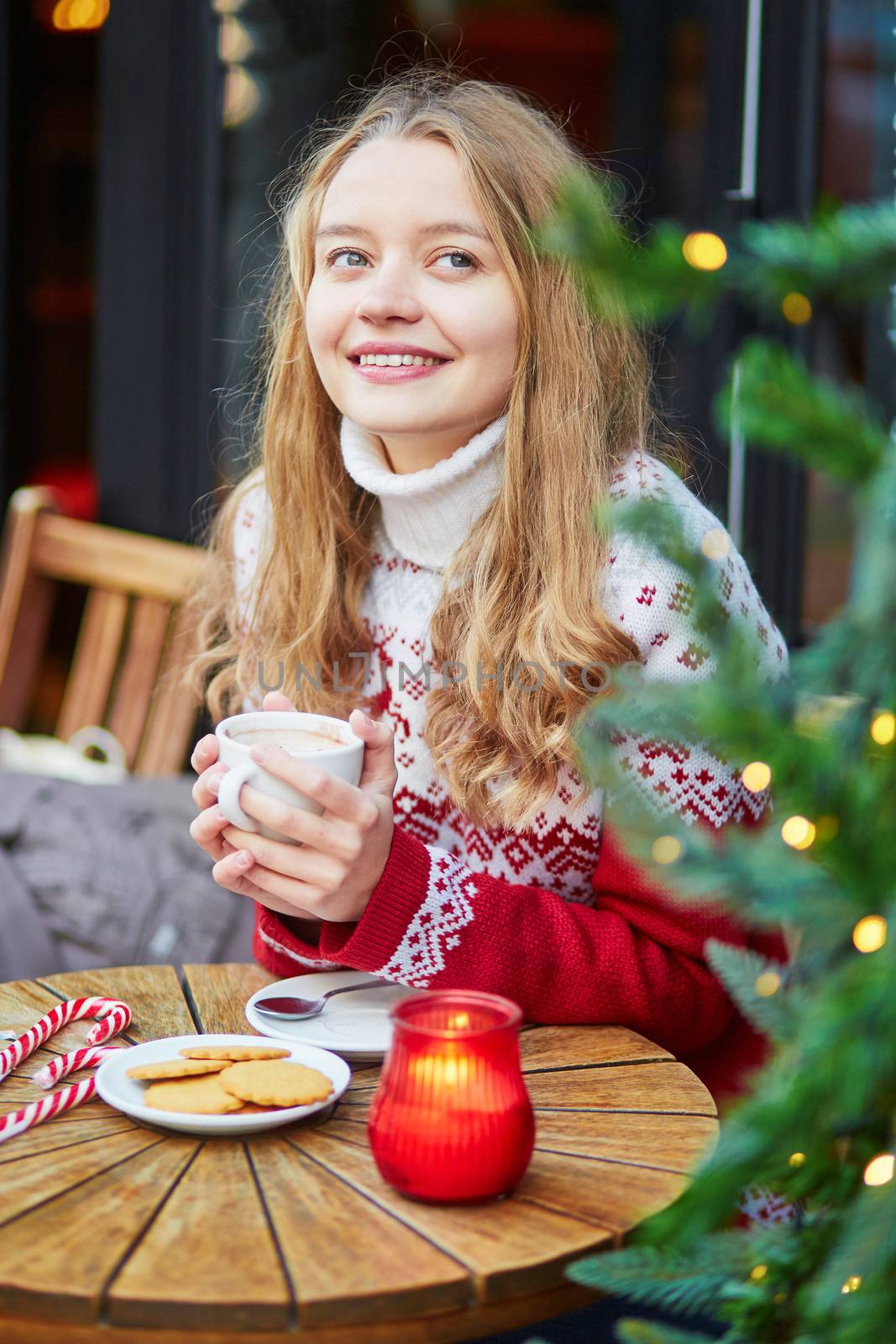 Beautiful young girl in an outdoor Parisian cafe on a winter day, drinking hot chocolate