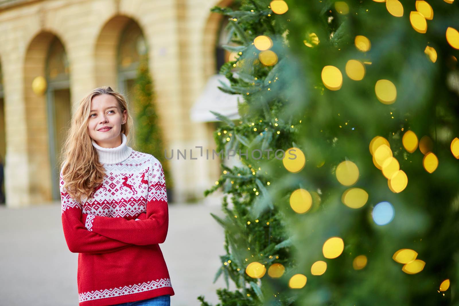 Girl with a brightly decorated Christmas tree in Paris
