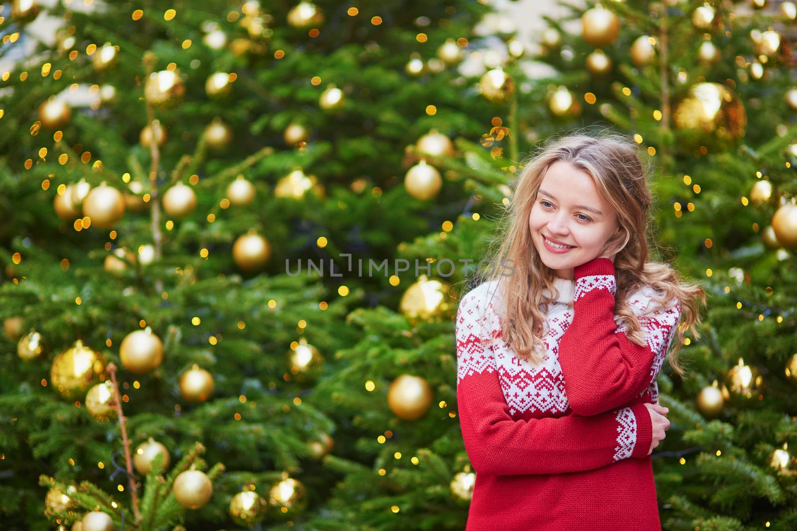 Girl with a brightly decorated Christmas tree in Paris