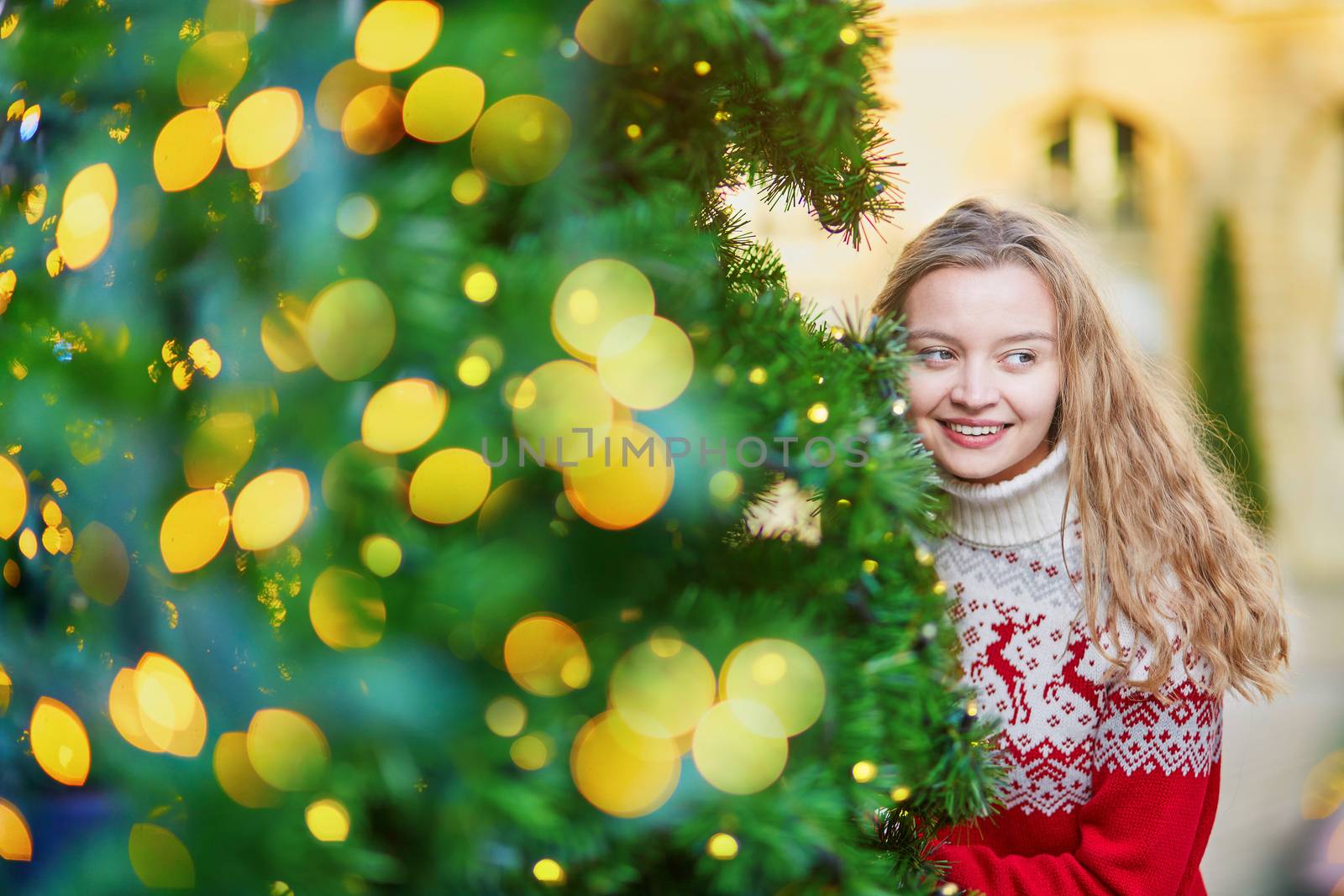Girl with a brightly decorated Christmas tree in Paris