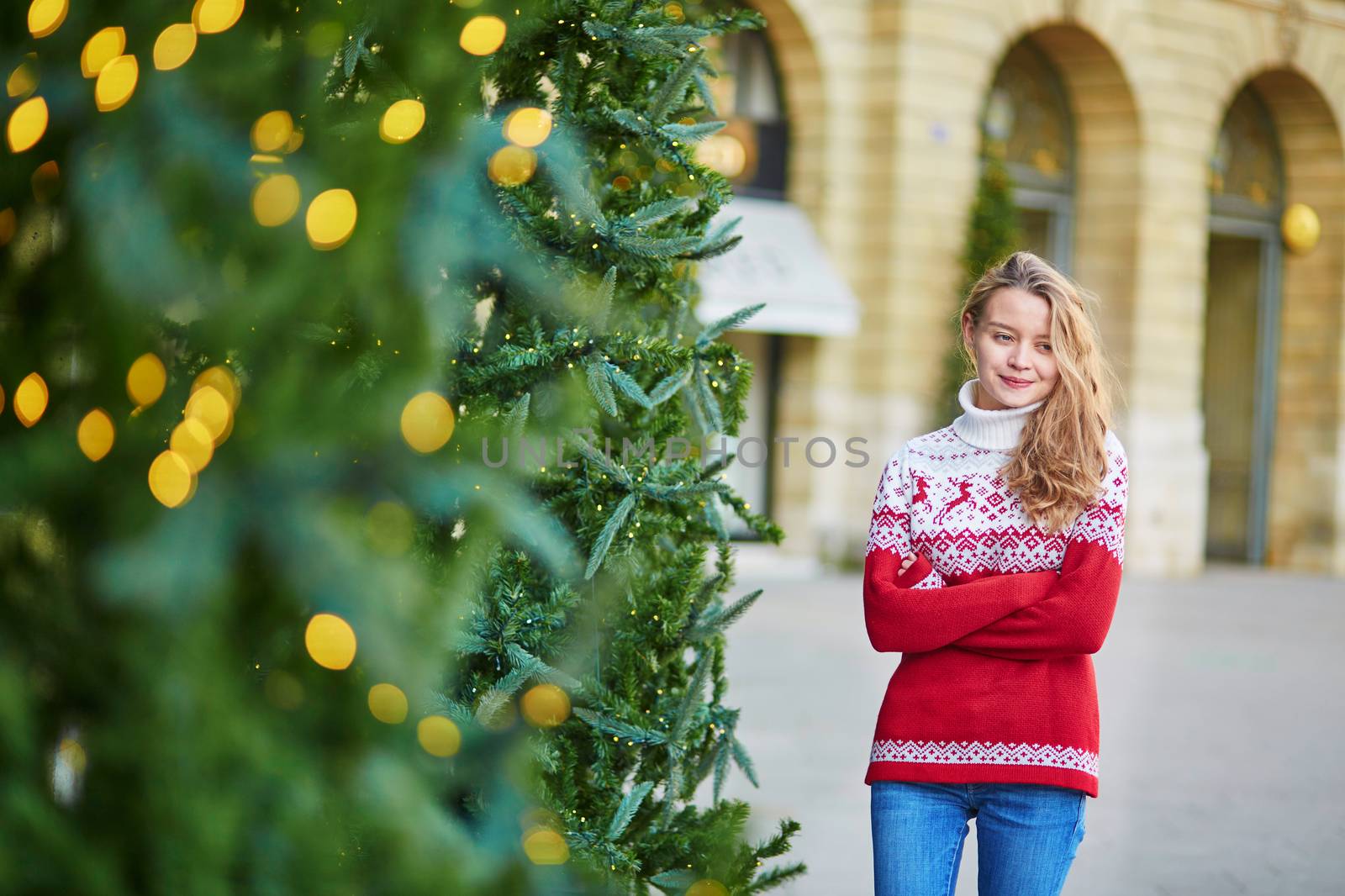 Cheerful young woman on a street of Paris decorated for Christmas
