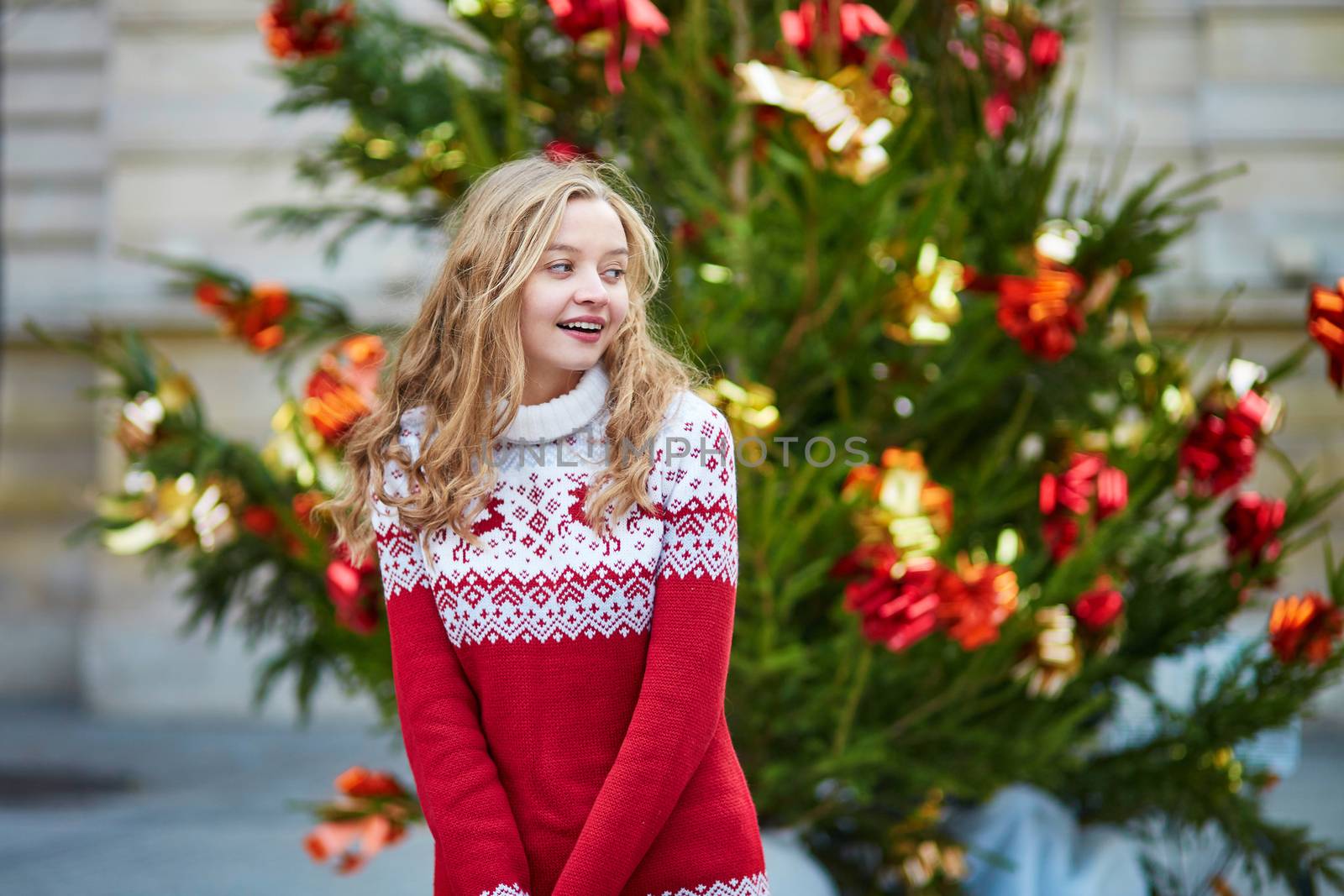 Girl with a brightly decorated Christmas tree in Paris