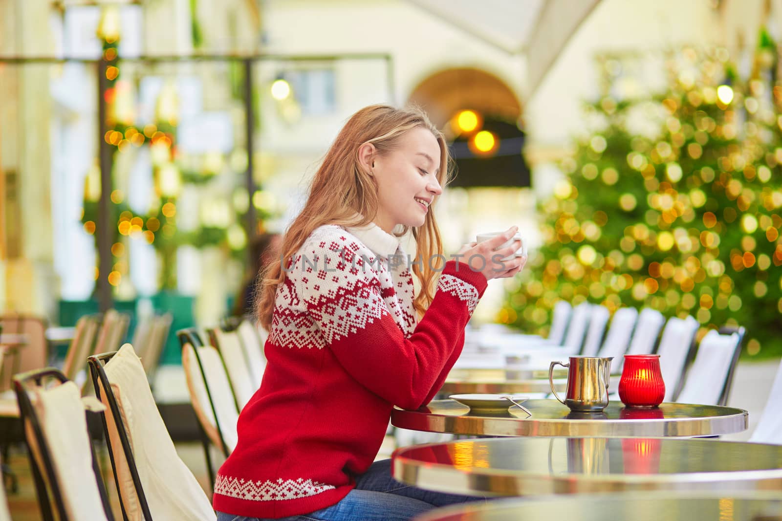 Beautiful young girl in an outdoor Parisian cafe on a winter day, drinking hot chocolate