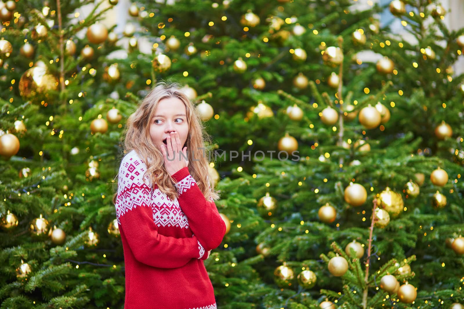 Astonished girl with a brightly decorated Christmas tree