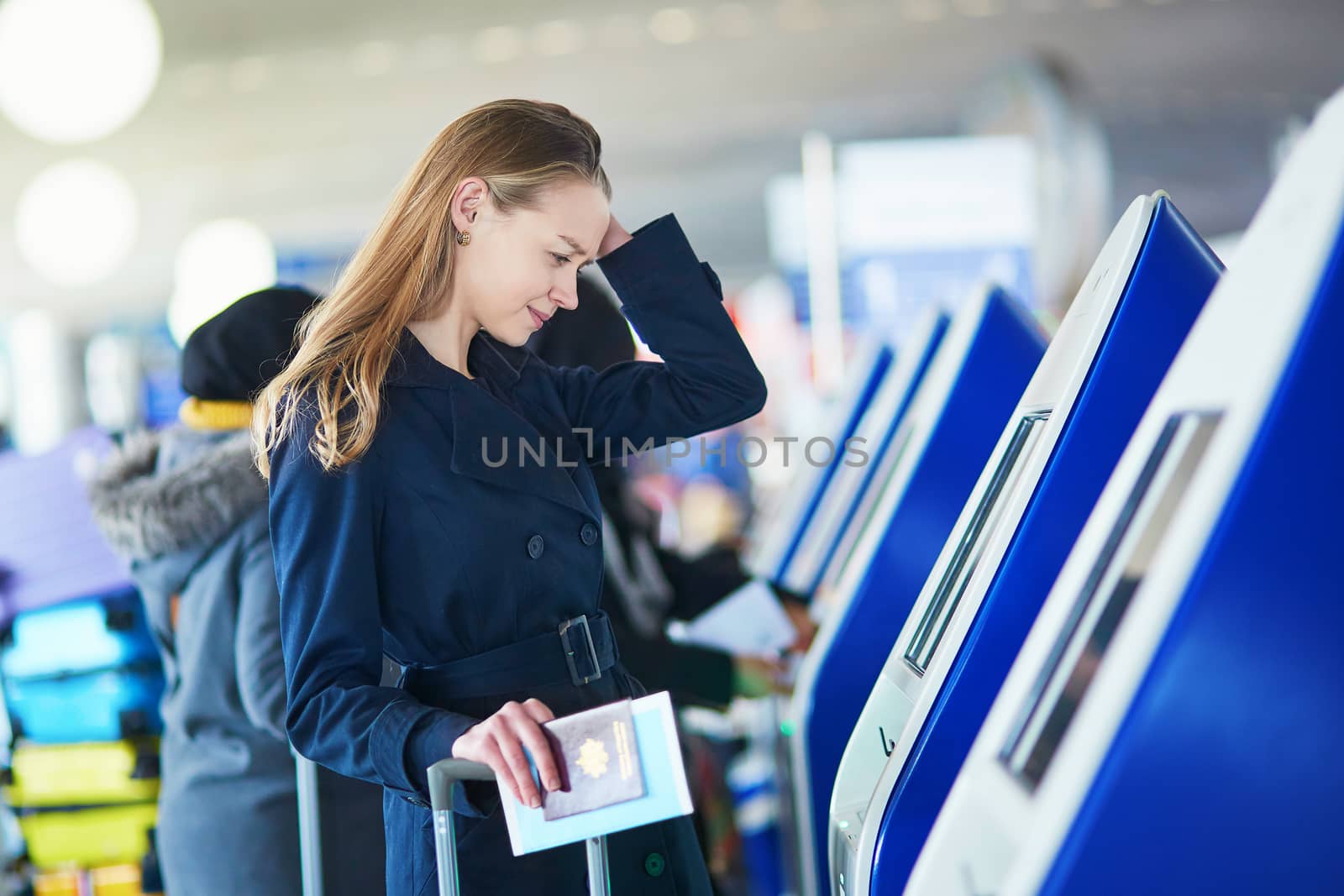 Young woman in international airport doing self check-in, stressed and concerned. Missed, delayed or canceled flight concept