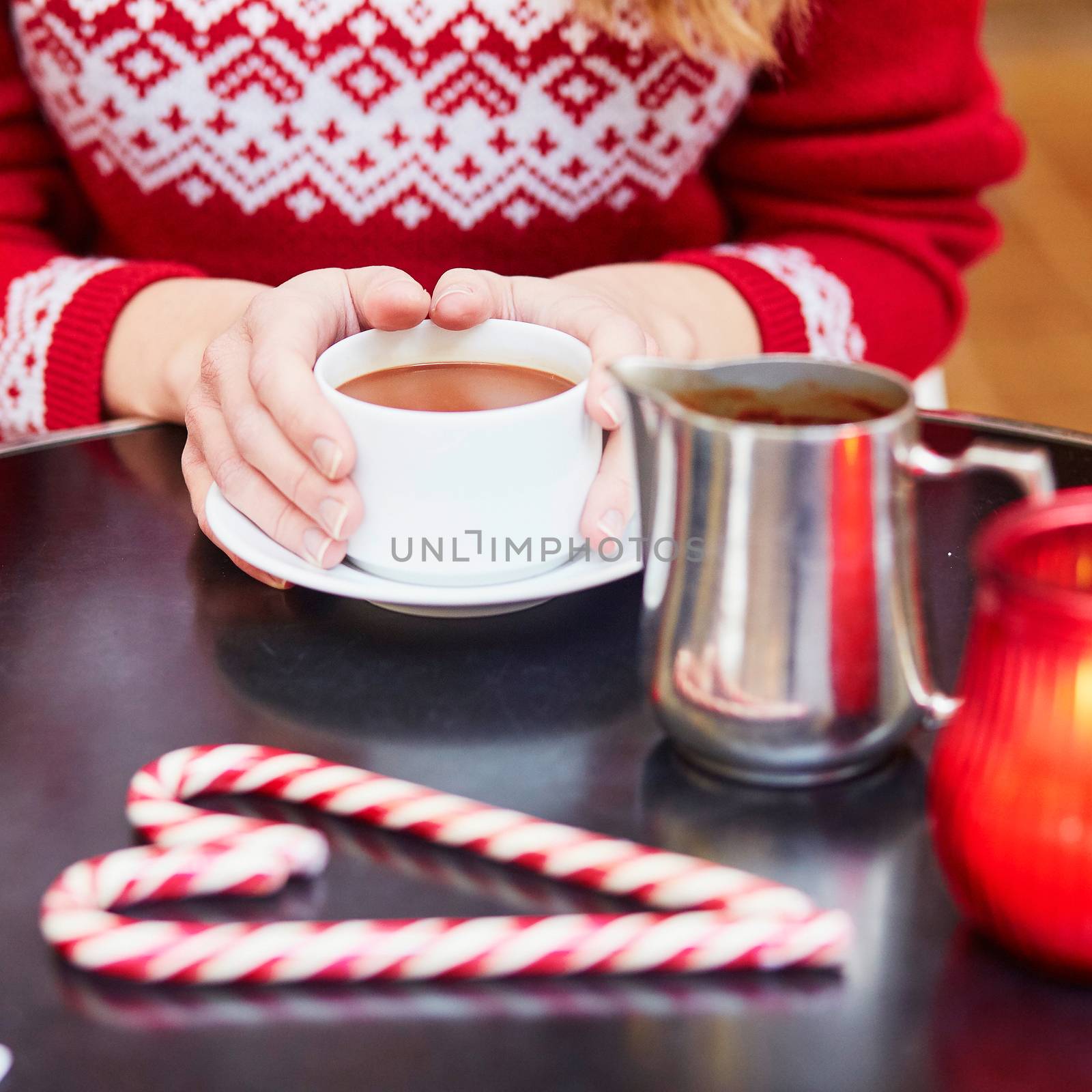 Woman drinking hot chocolate in a cozy outdoor Parisian cafe decorated for Christmas