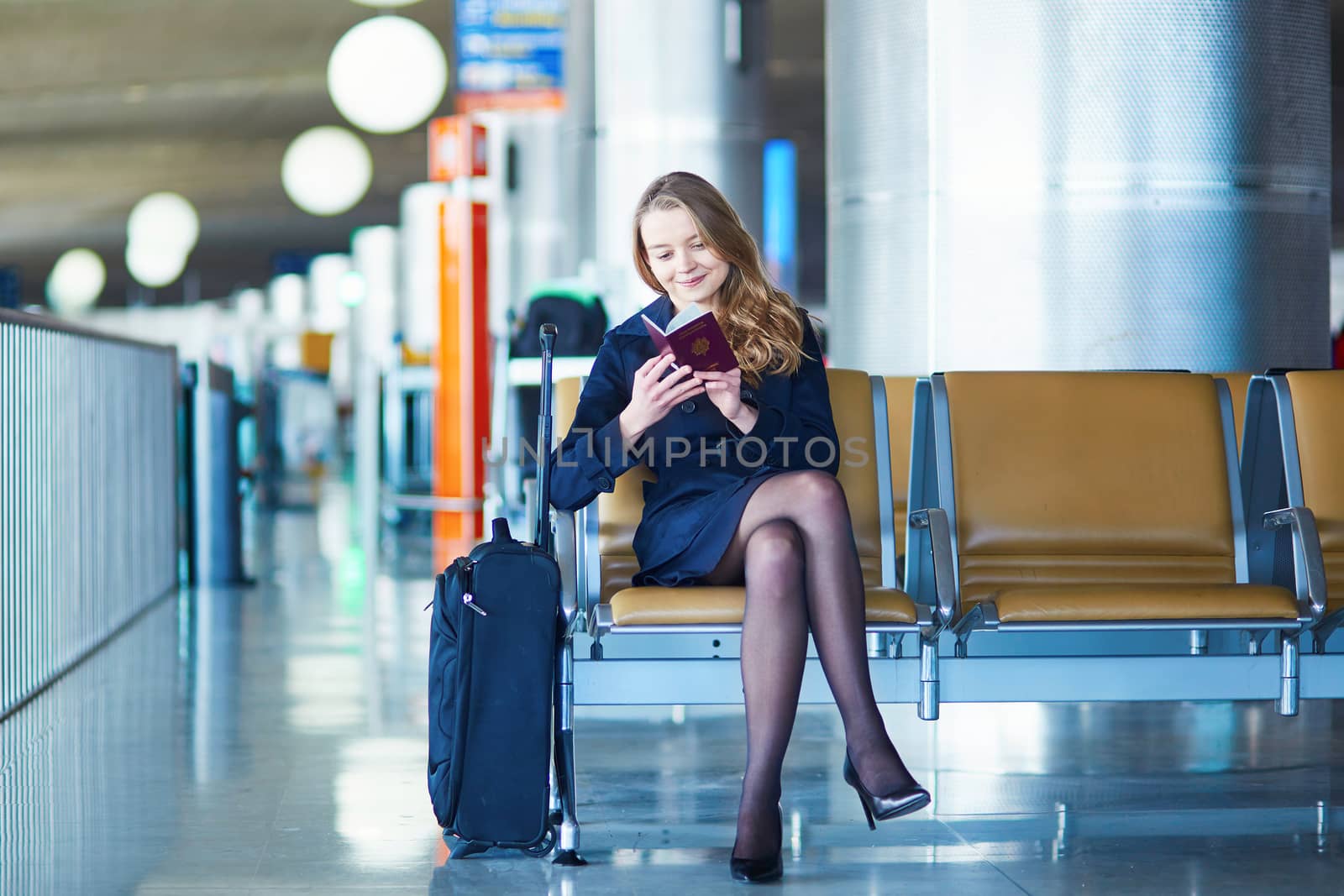 Young woman in international airport, waiting for her flight, looking in her passport