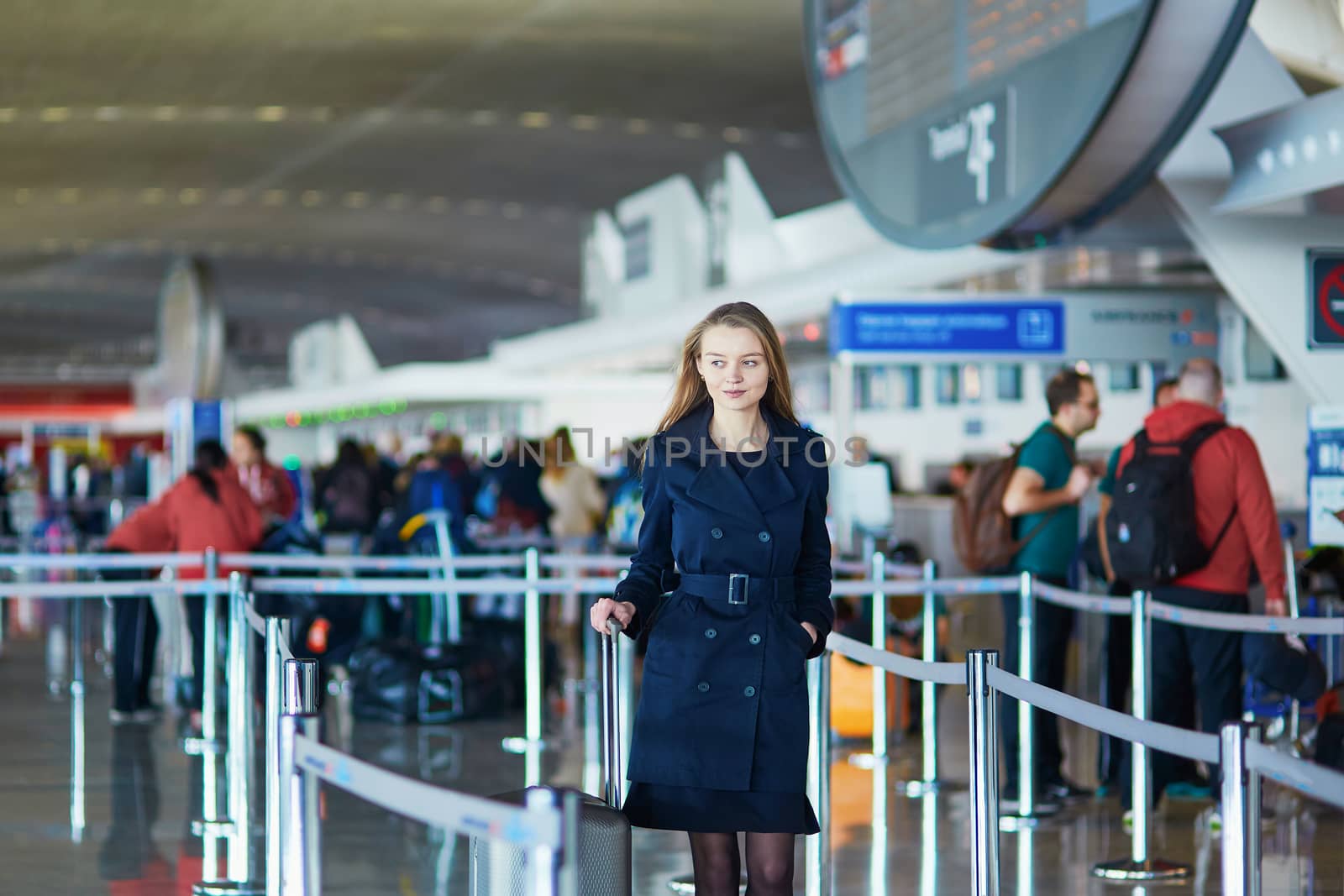 Young woman in international airport, walking with her luggage