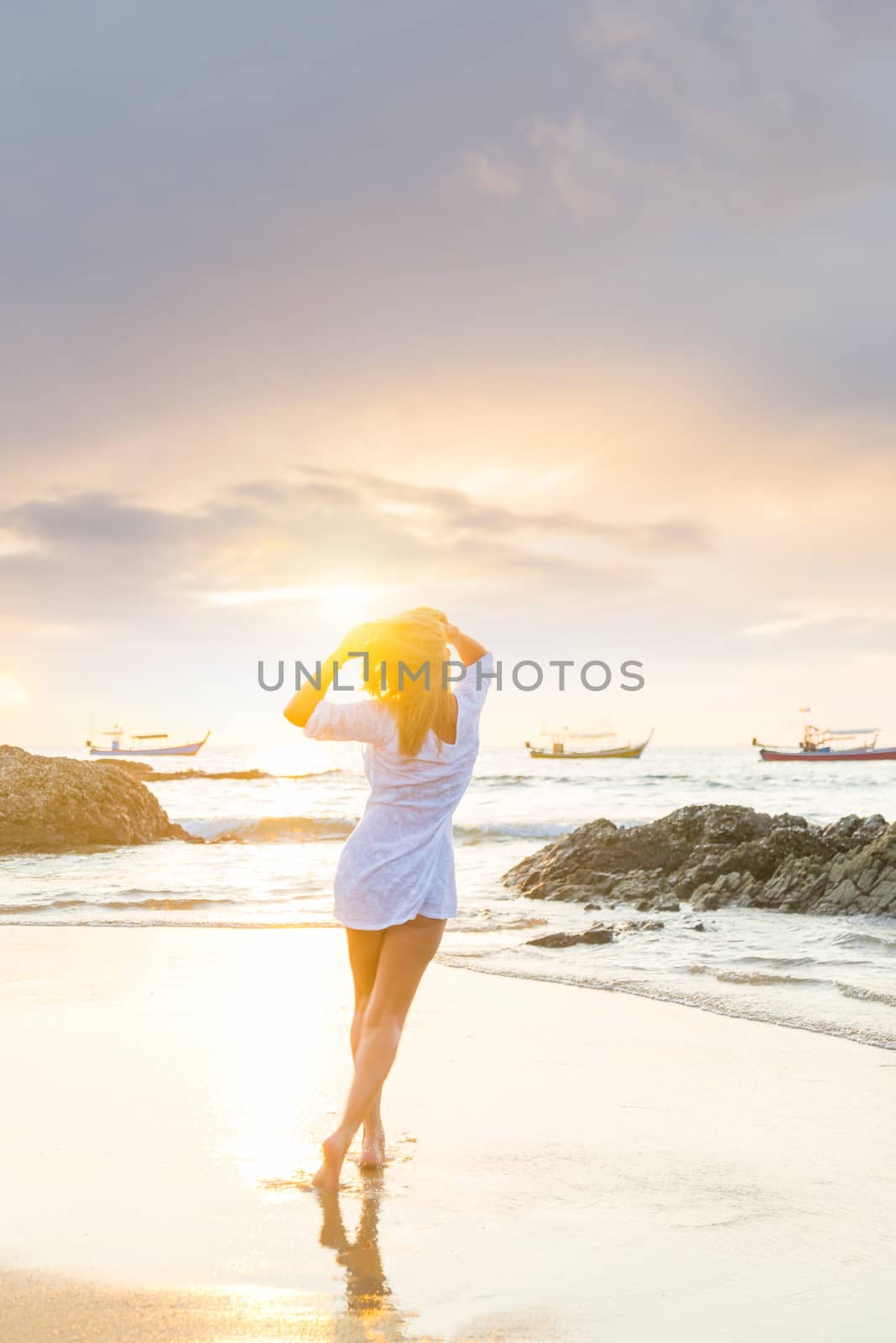 Woman walking on the tropical beach at sunset 